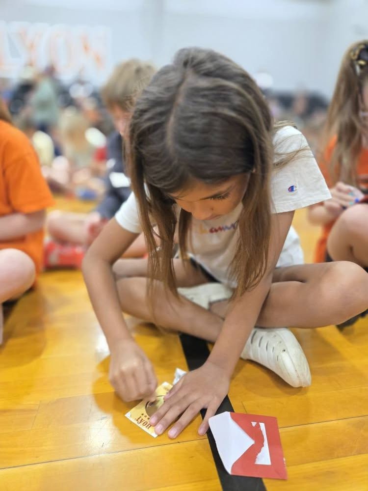 Female student with dark hair scratching her Lead Team reveal ticket.