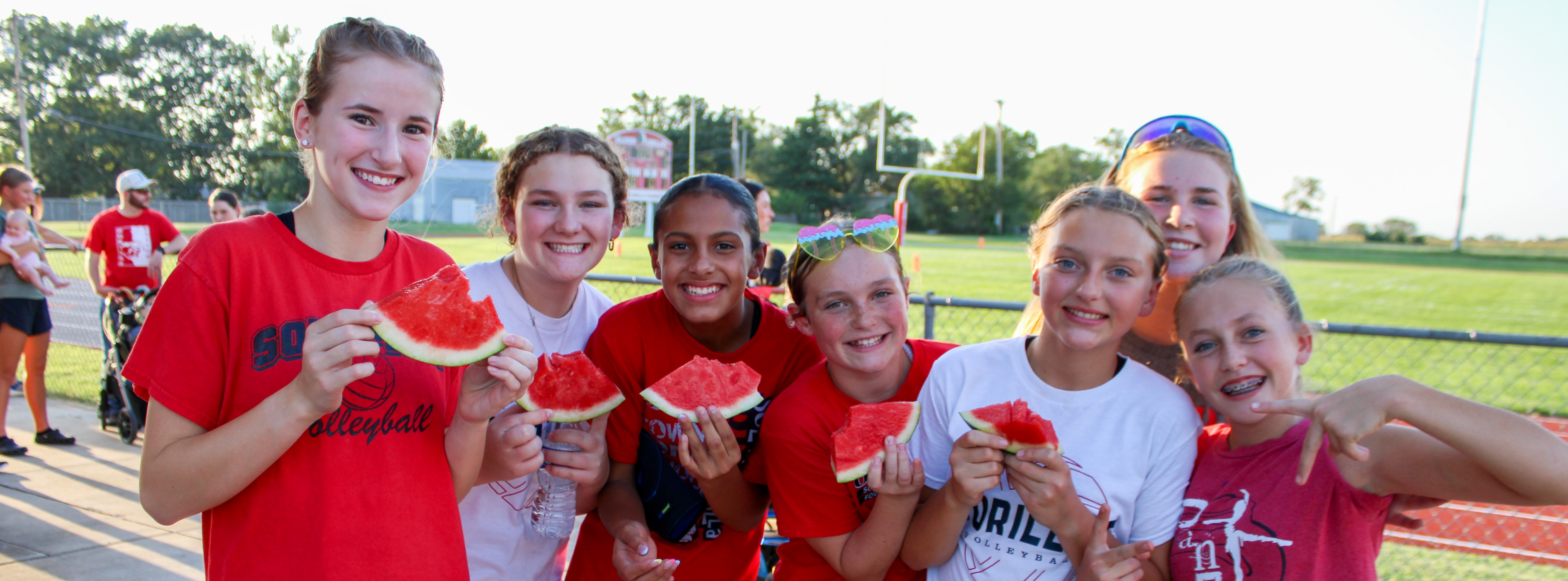 group of students holding watermelon slices and smililing