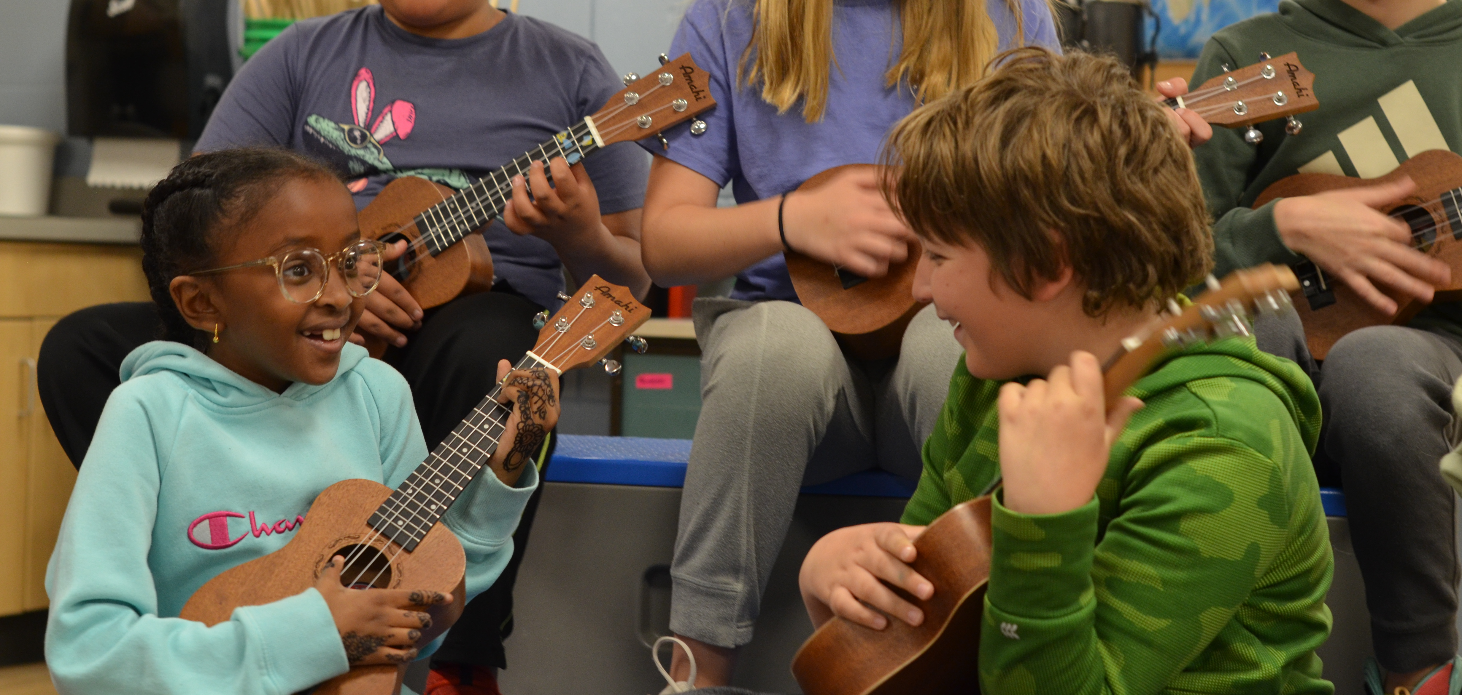 Students playing the ukulele in music class while singing.