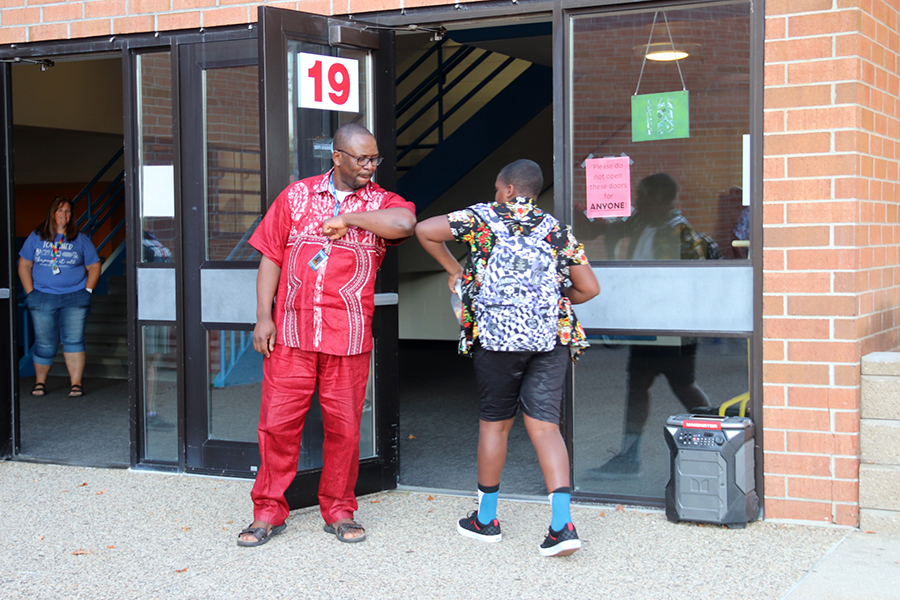 RPS staff person elbow-high-fiving a student as they enter the building