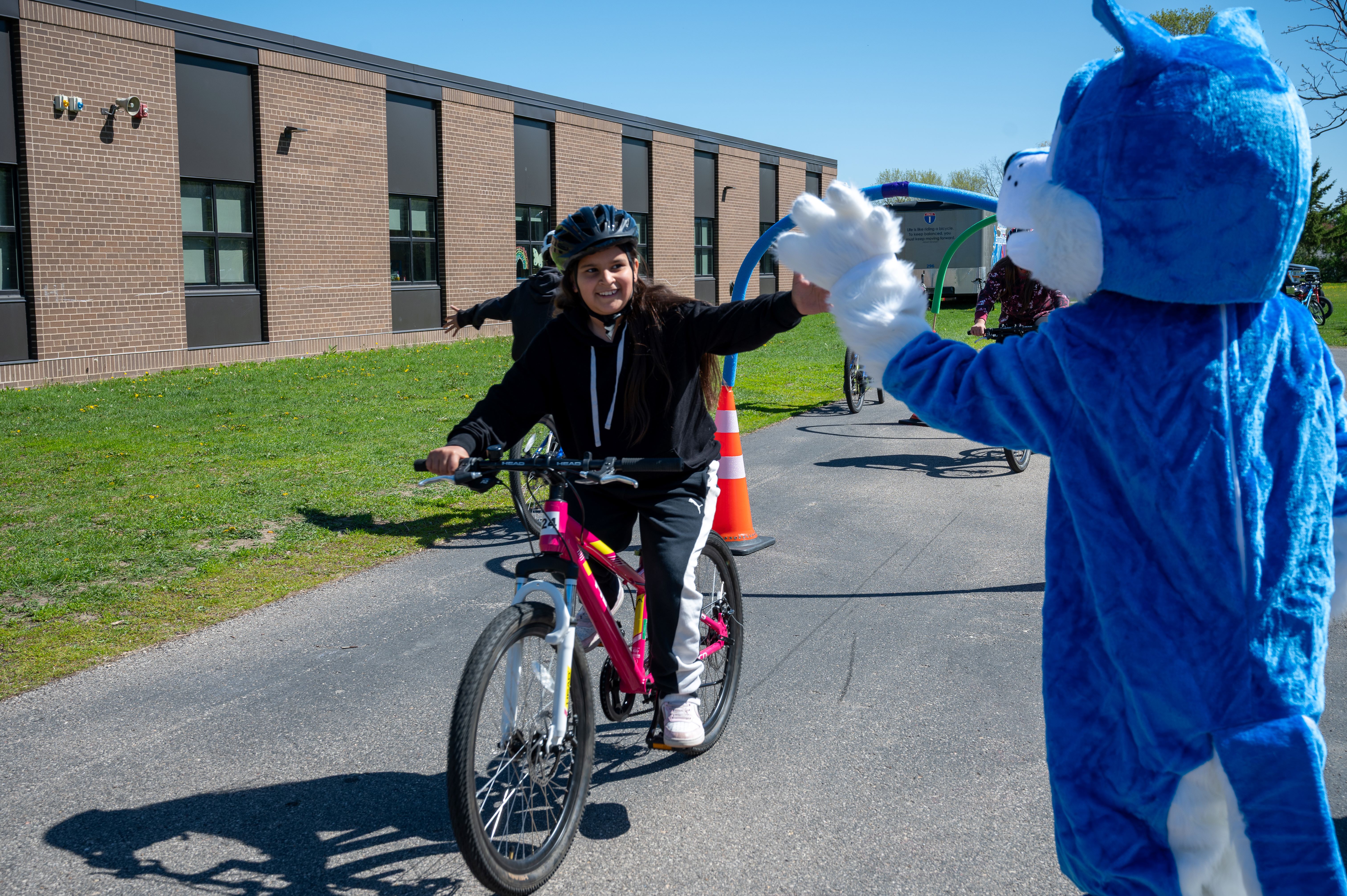 girl on bike, high five to mascot
