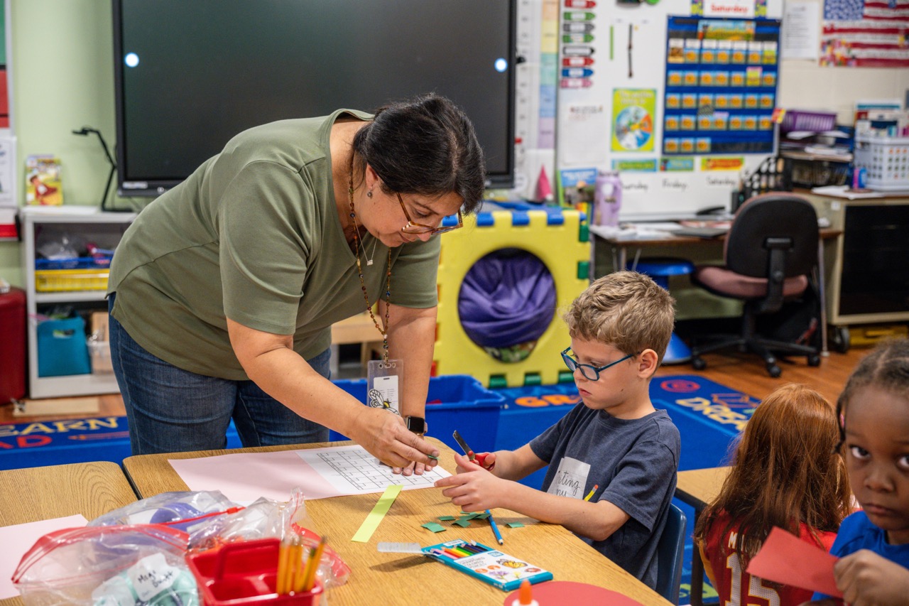 Teacher helping a student at the student's desk