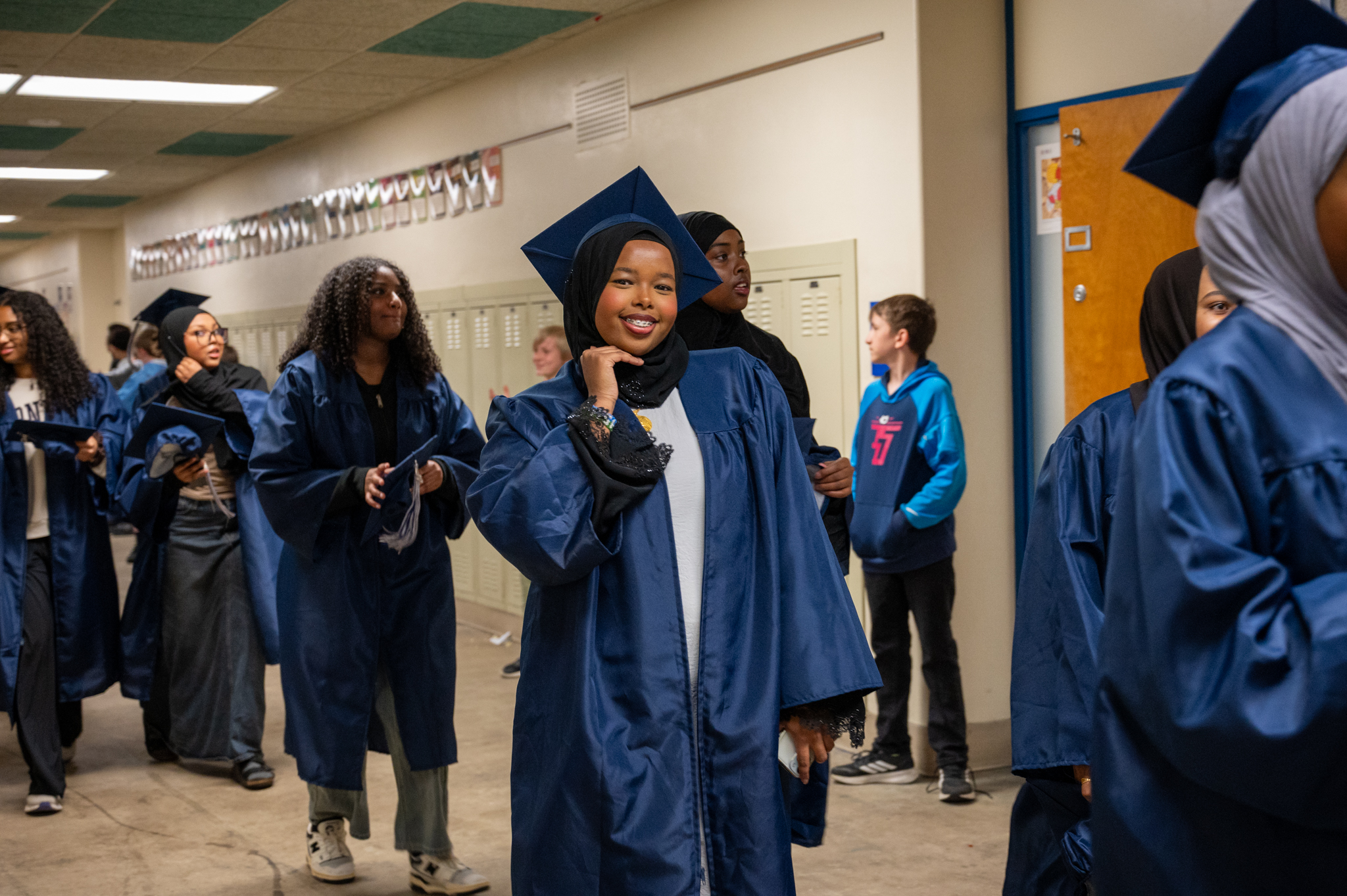 Student posing for a photo in their cap and gown during senior walk