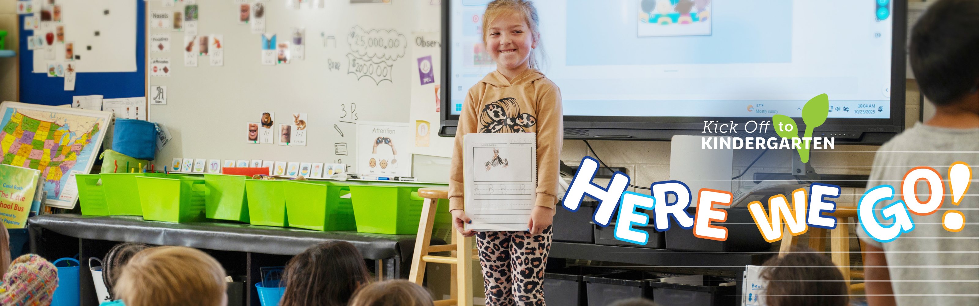 Student in front of the classroom smiling with their picture in their hands with text overlay "Here we go!"