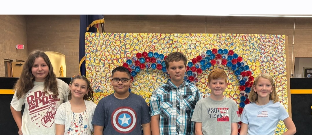 Middle Schoolers posing in front of a background with red and blue circles in the shape of a heart in front of a white background for a Remembering 9/11
