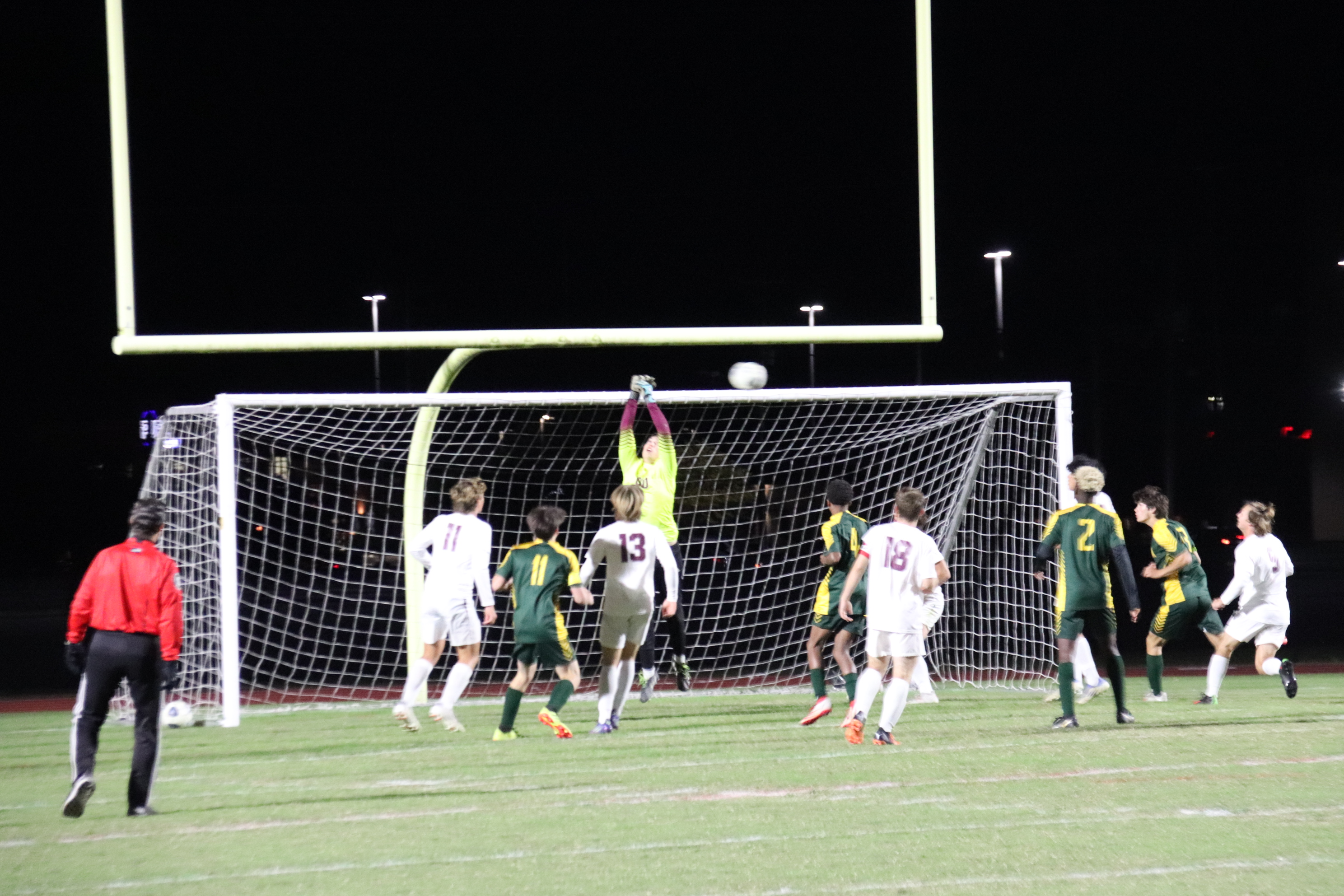 players watch the soccer ball approach the goal