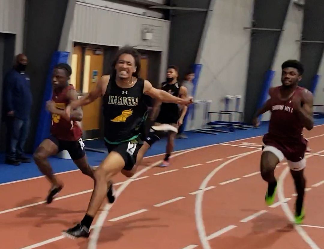 boys cross the finish line of a high school indoor track race