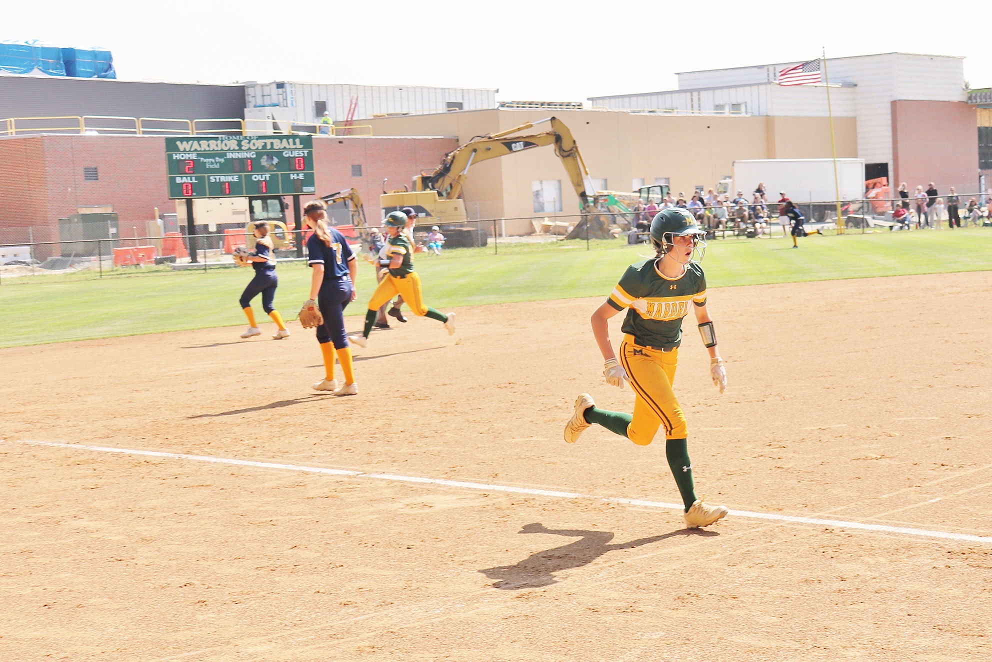 softball player is running toward home plate