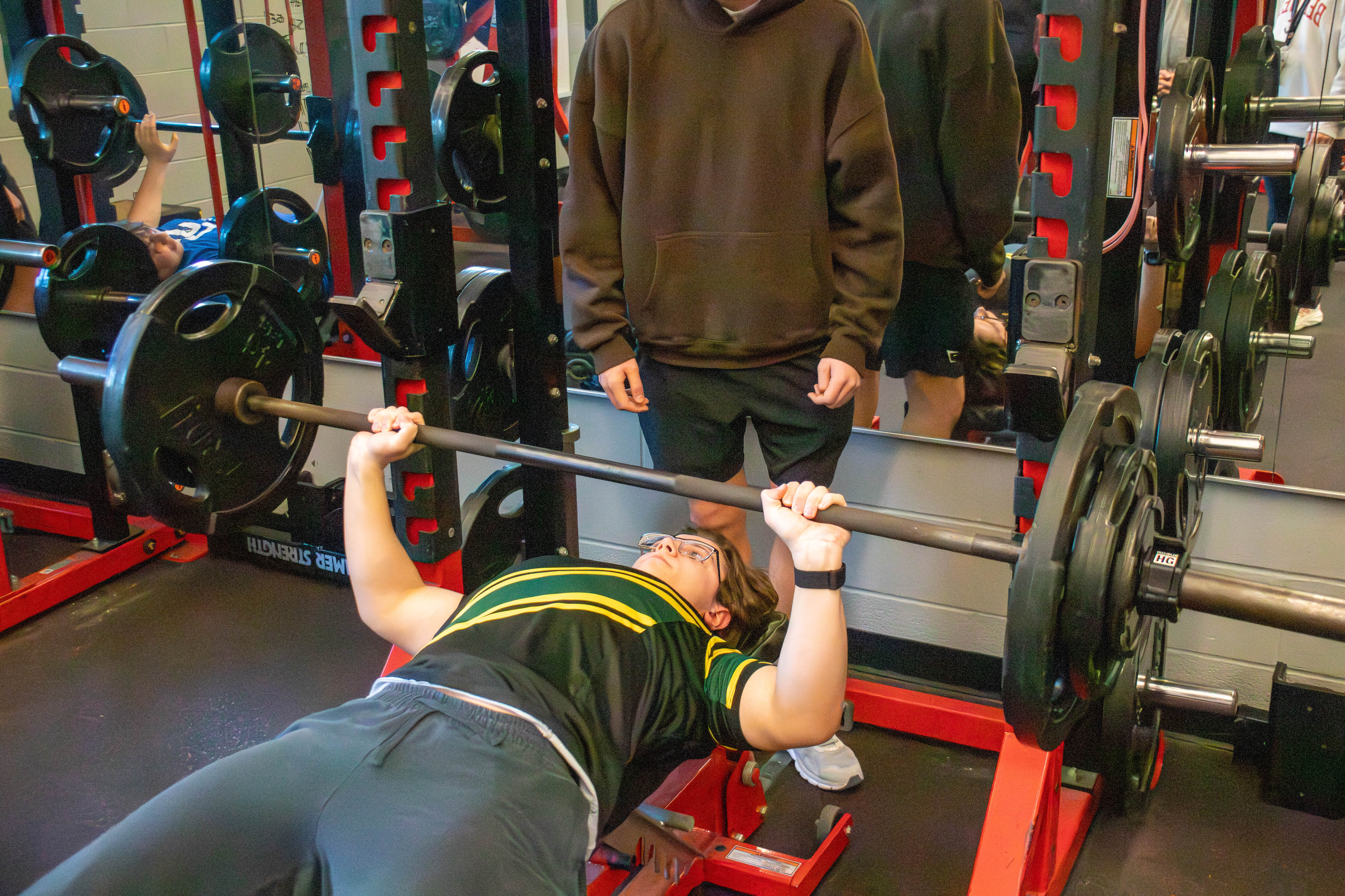 Image of high school boy doing a bench press in the weight room