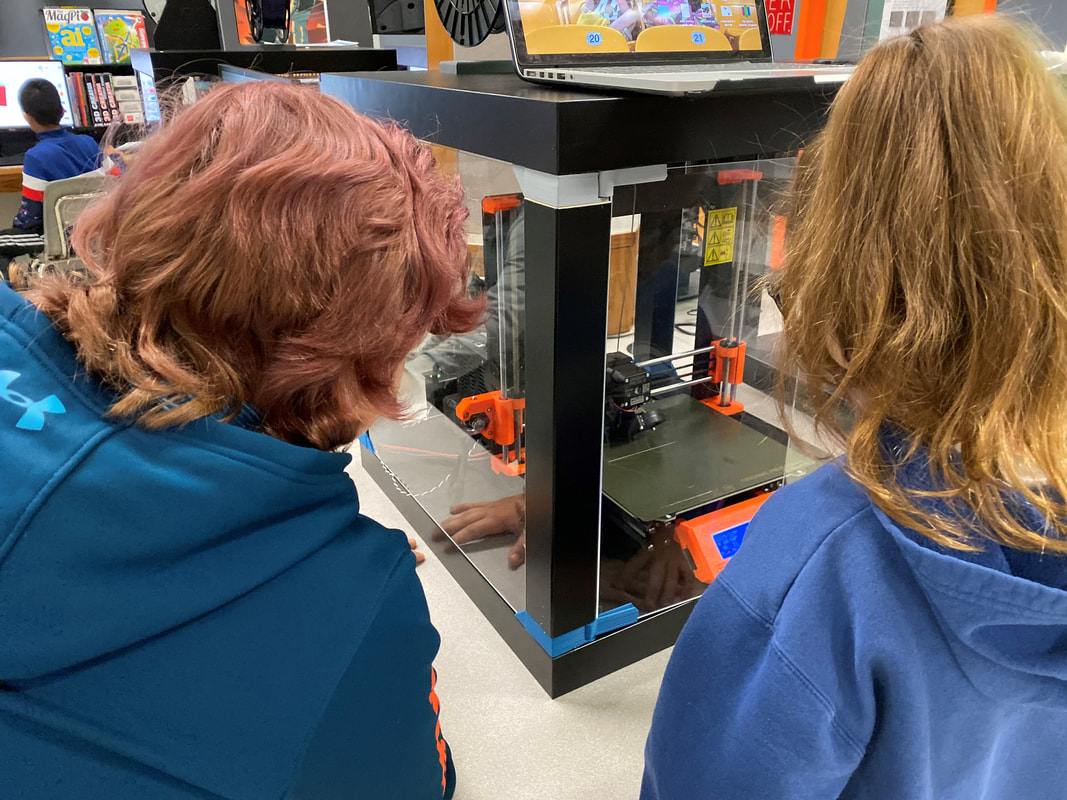 Image of students looking at a 3D Printer 