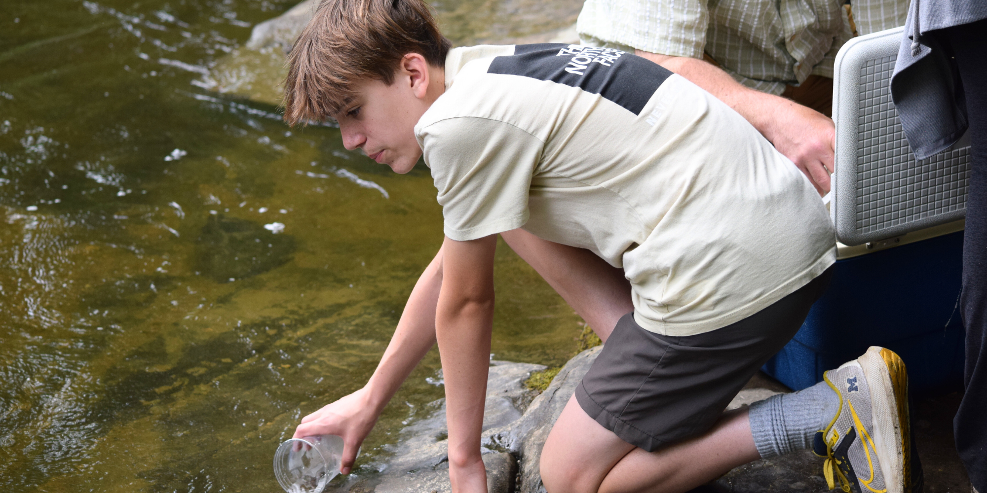 Student releasing a trout into the stream