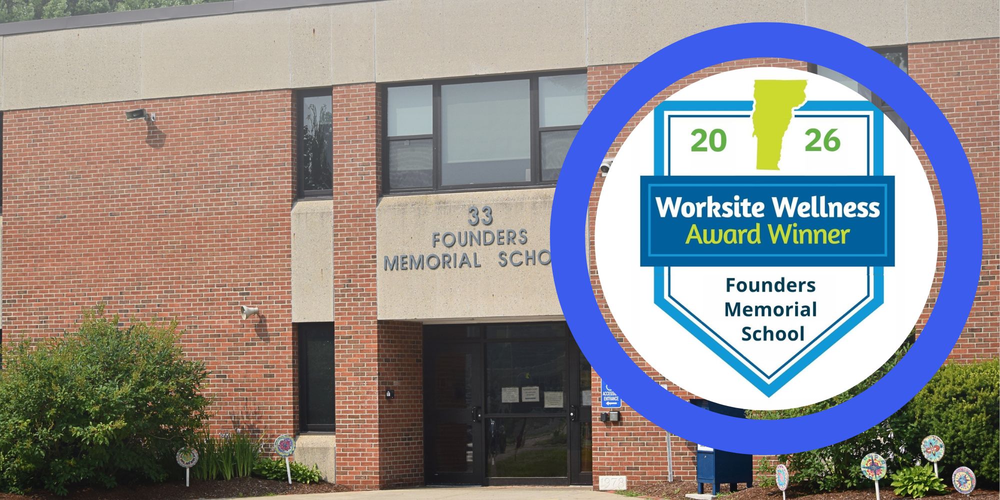 A brick building with a sign reading "Founders Memorial School". A circular emblem with "Worksite Wellness Award Winner" is placed near the entrance.