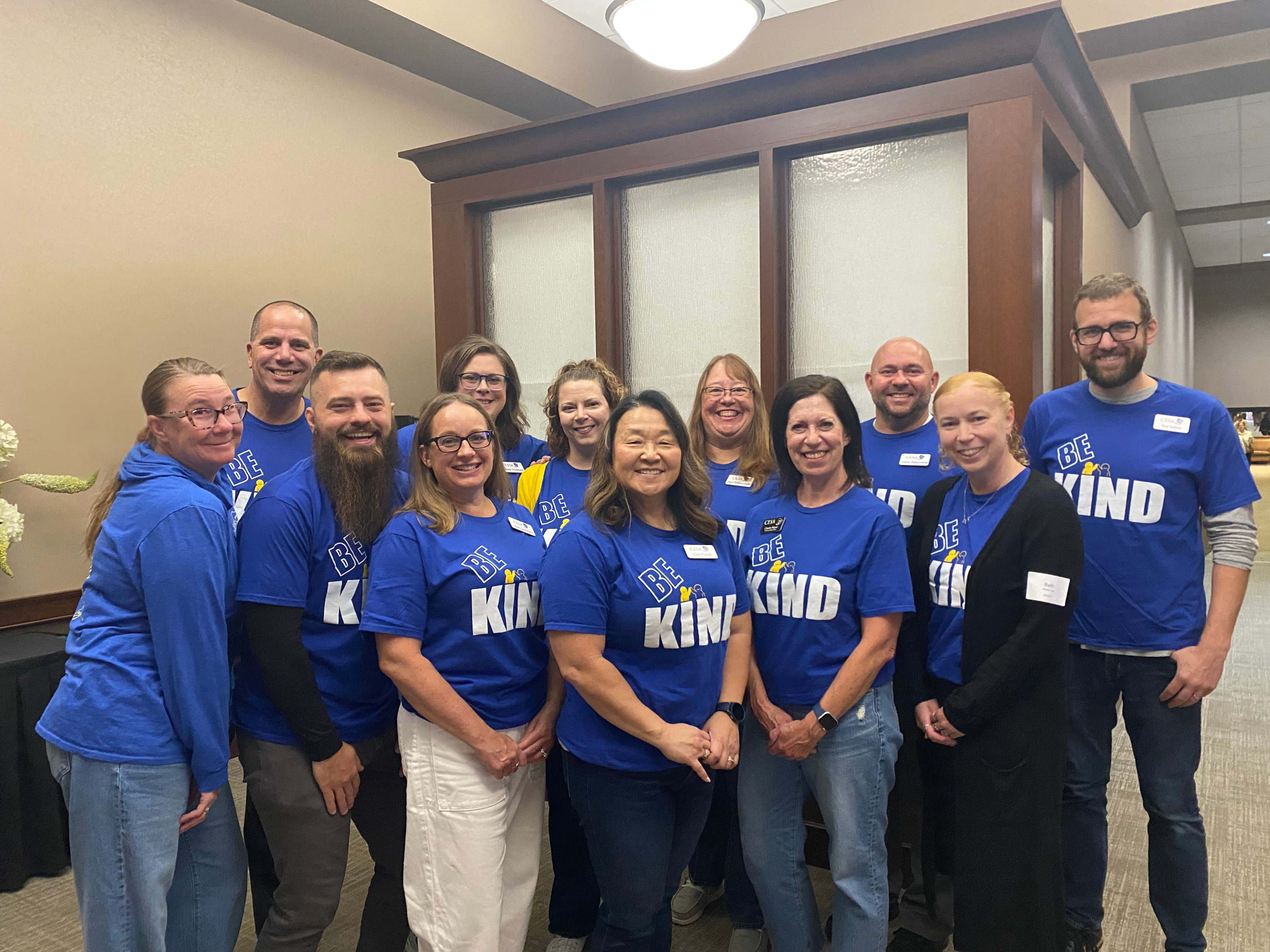 Group of CESA 7 staff standing shoulder to shoulder wearing blue Be Kind t-shirts.