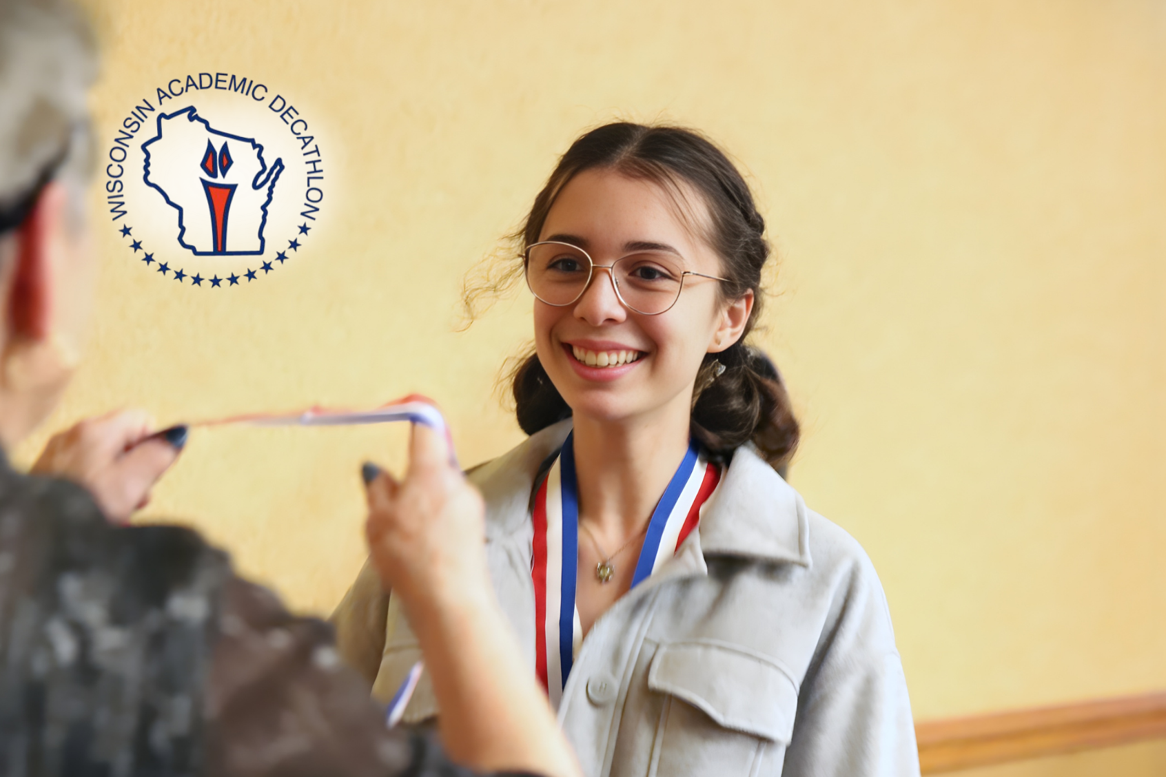 Smiling student wearing an award ribbon about to receive another award
