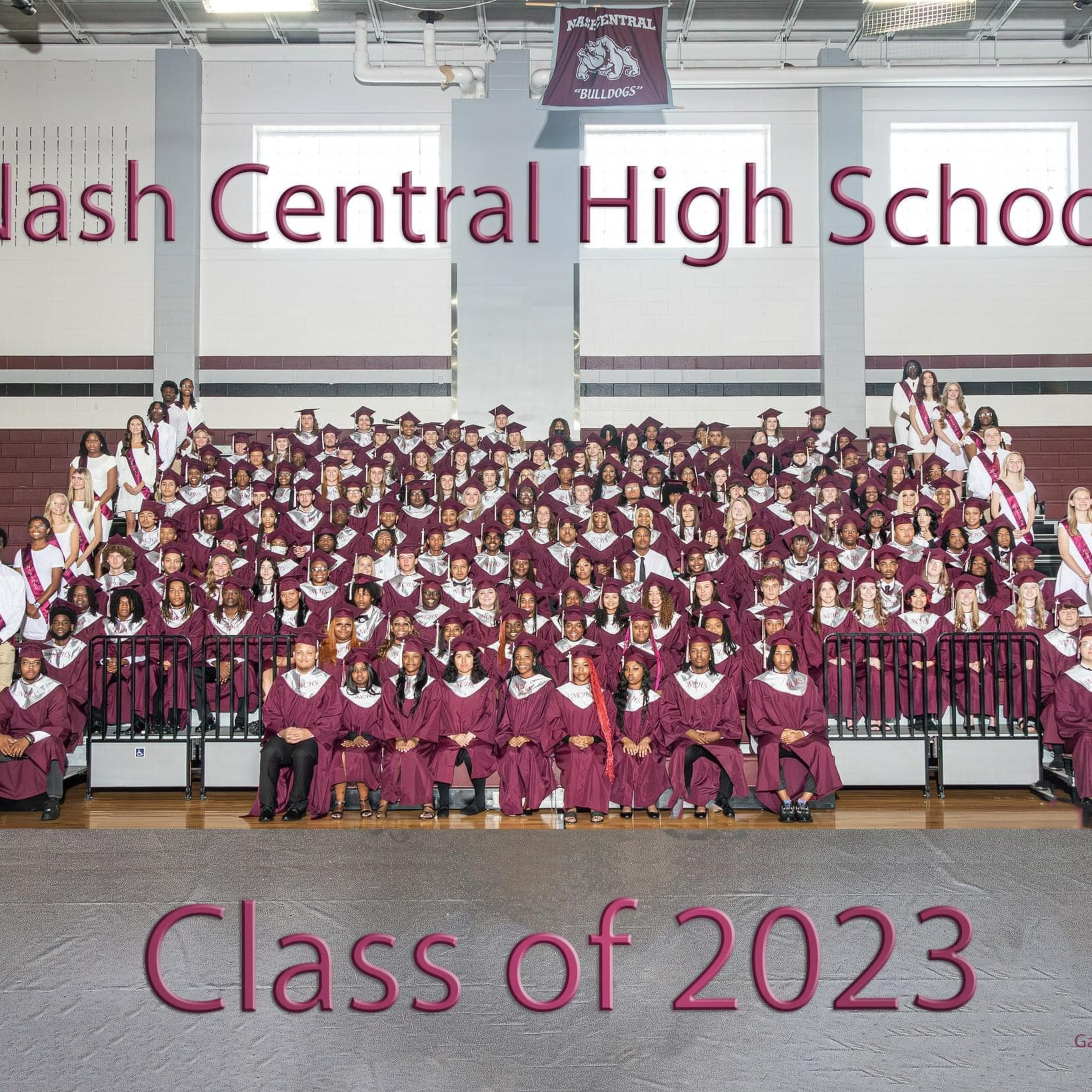 Class of 2023 seniors sitting in bleachers in caps and gowns