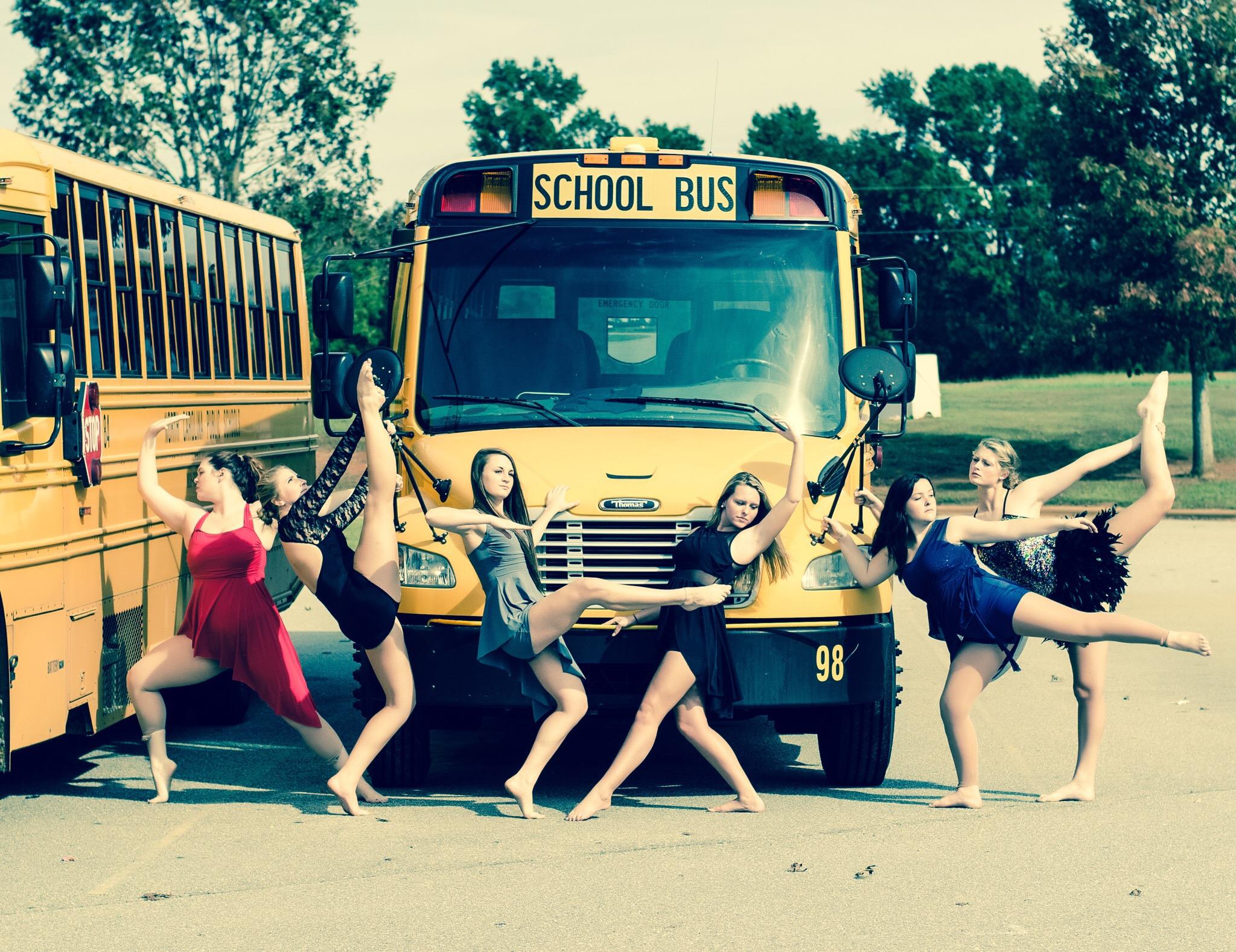 nchs dance company in front of a school bus