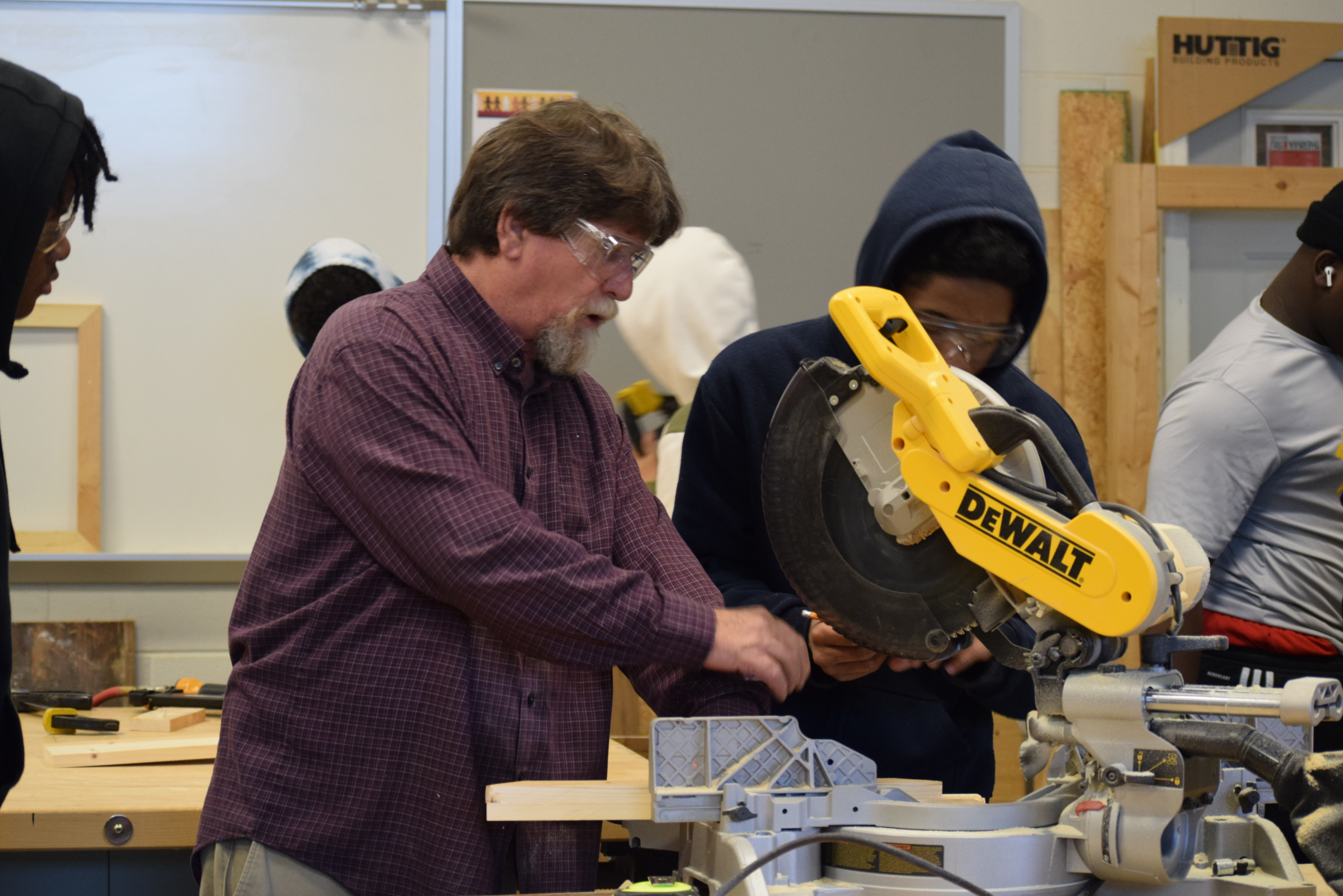 Carpentry teacher helping student use a piece of equipment