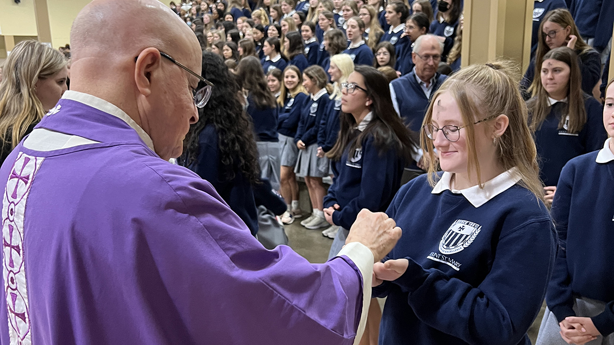 student receiving the Eucharist from Fr. Fred during an all-school Mass