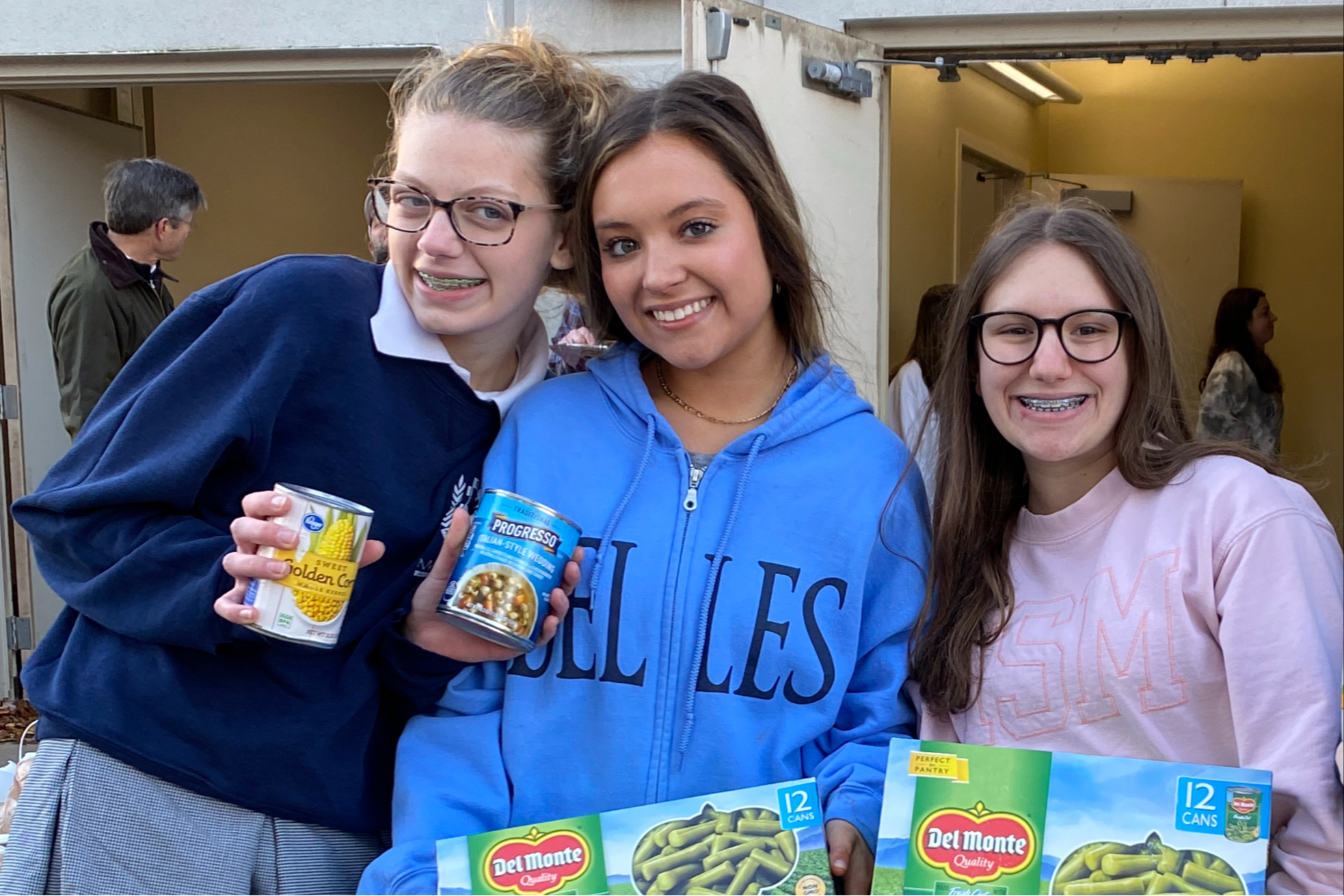 three students holding donated canned food