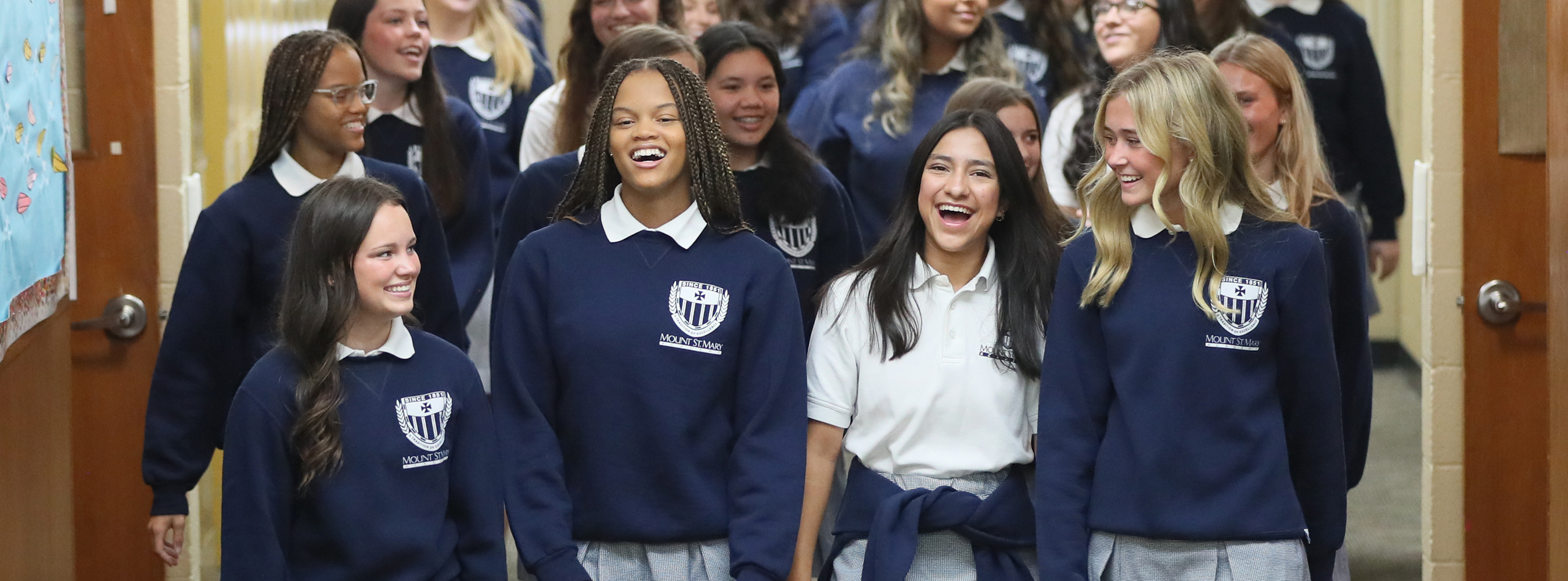 image of students smiling and talking while walking in hallway of school