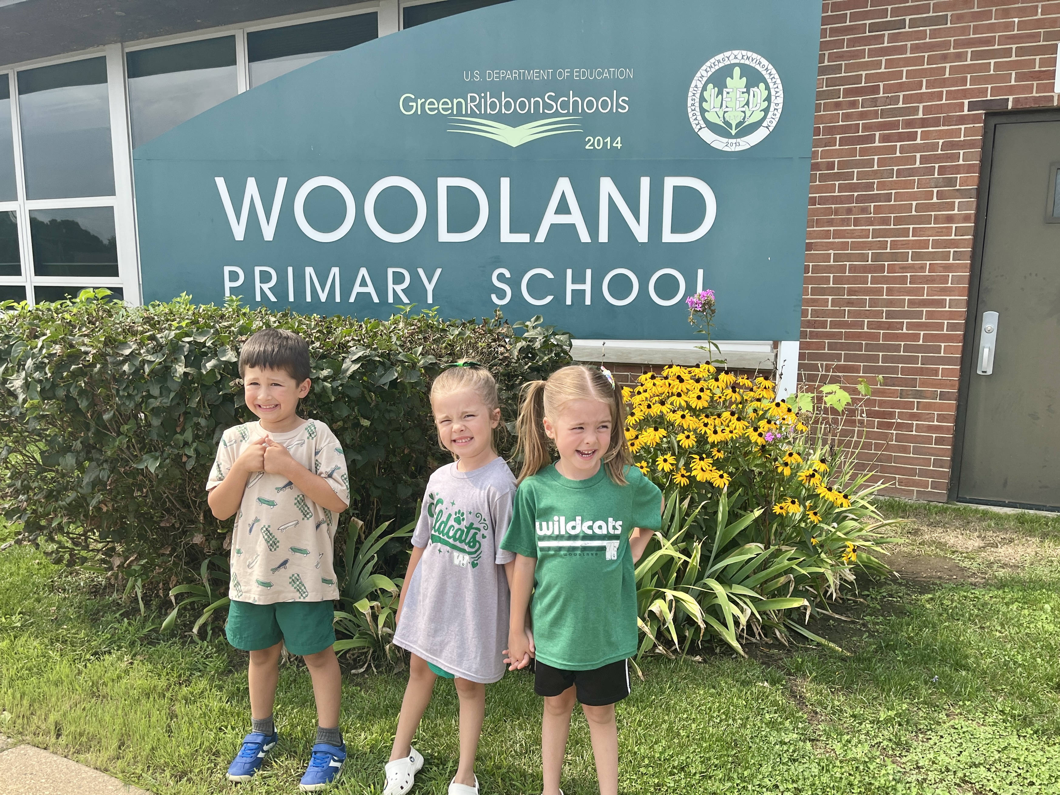 students in front of the weoold primary sign 