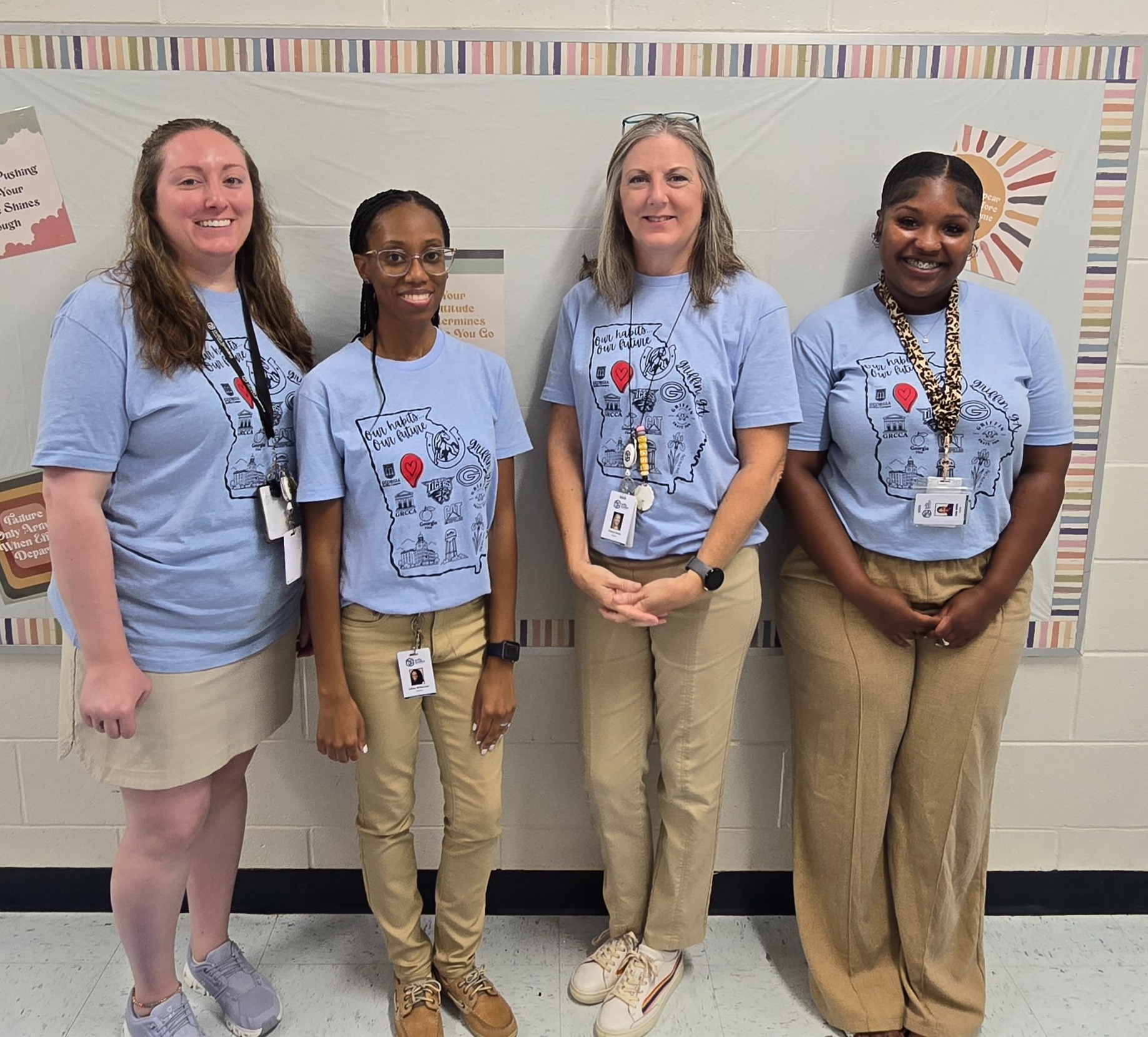 four teachers standing in hall in blue Cowan shirts