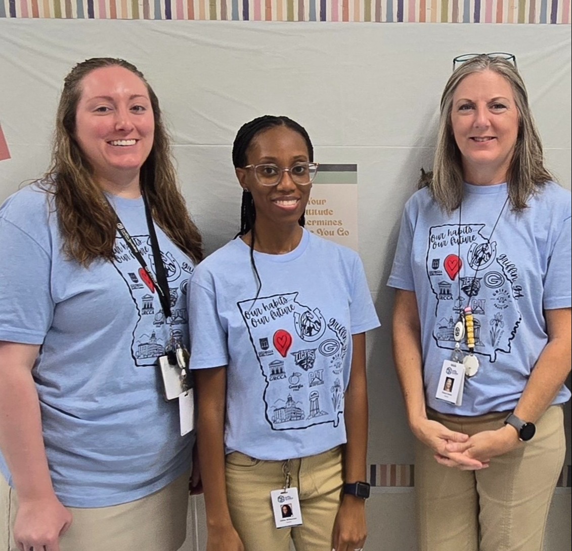 three teachers standing in hall in blue Cowan shirts