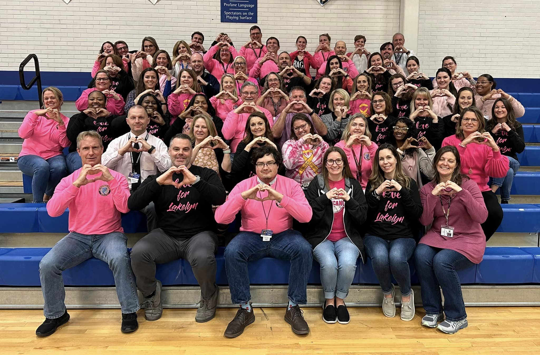 Staff in pink making hearts with their hands