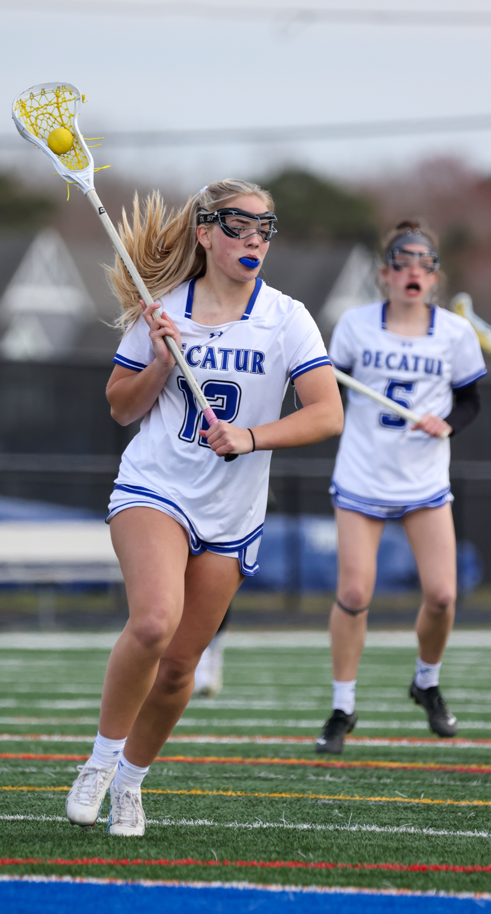 girl running down lacrosse field