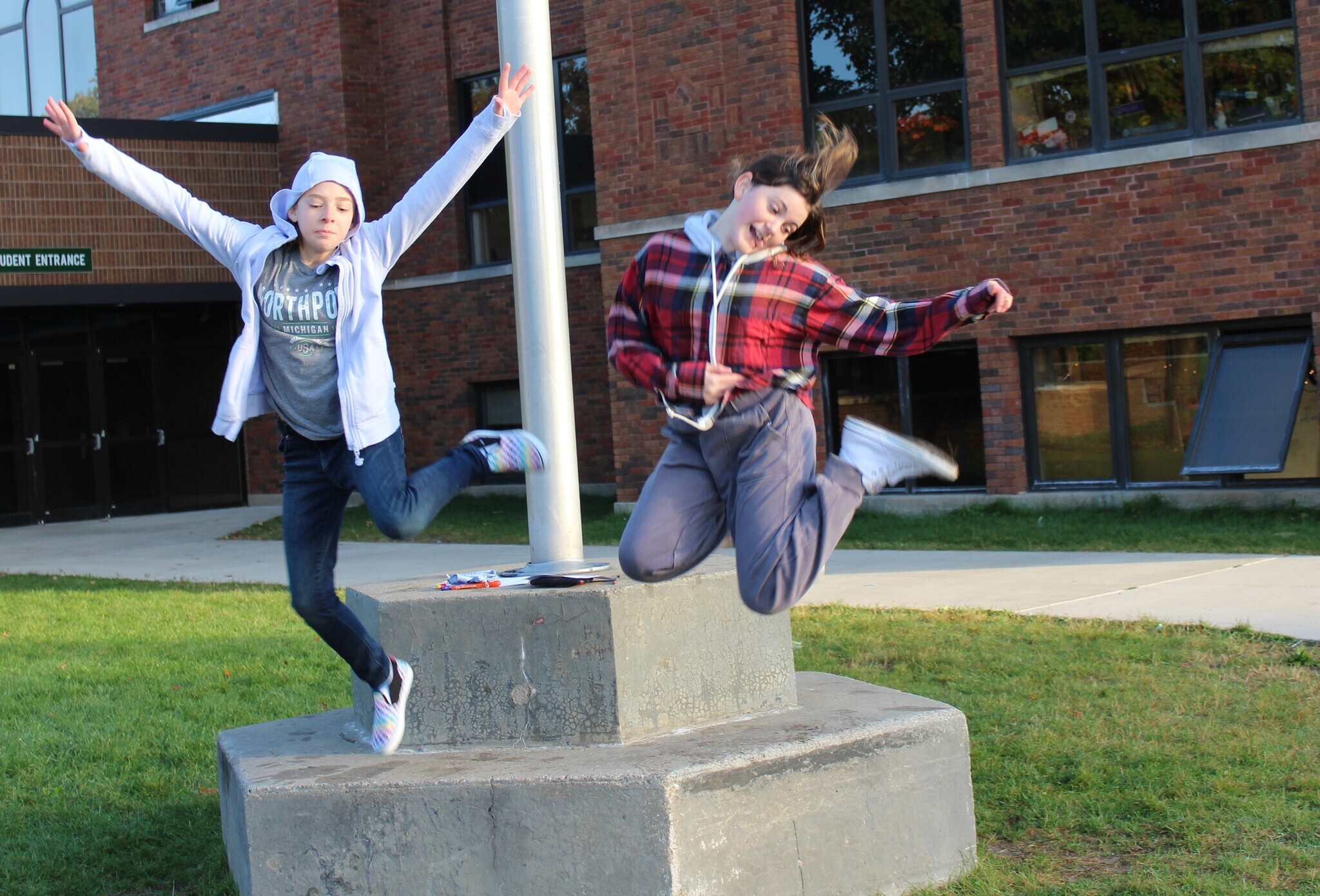 two students jumping with hands in the air