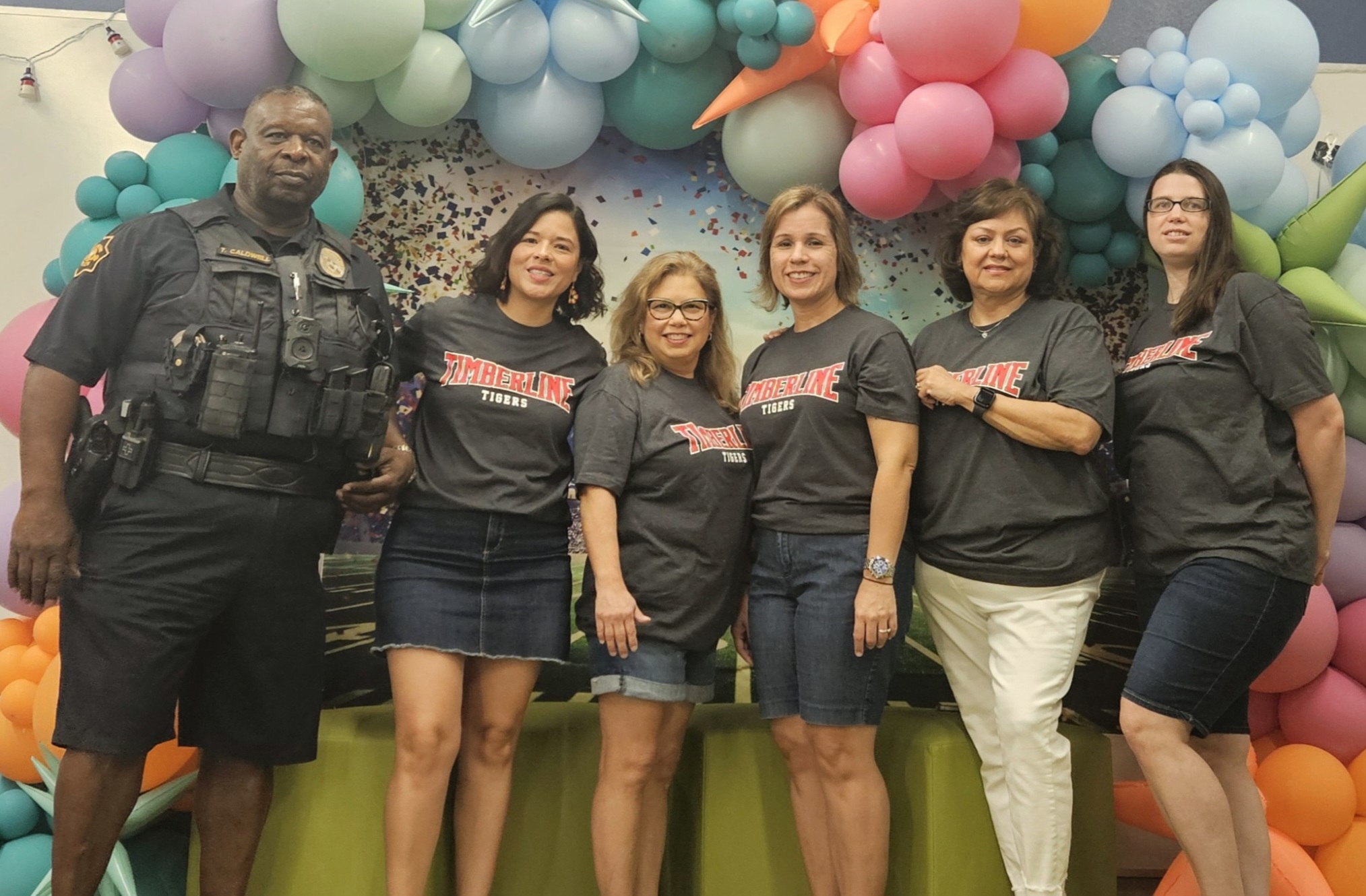 office staff poses in front of a balloon arch