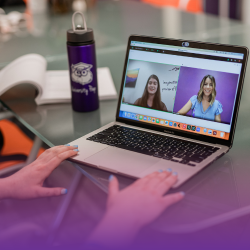 laptop on a desk with a teacher and student in a meeting room