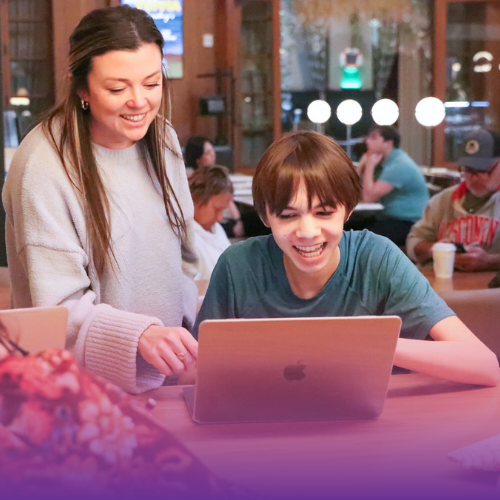 Teacher and student working on a laptop and smiling