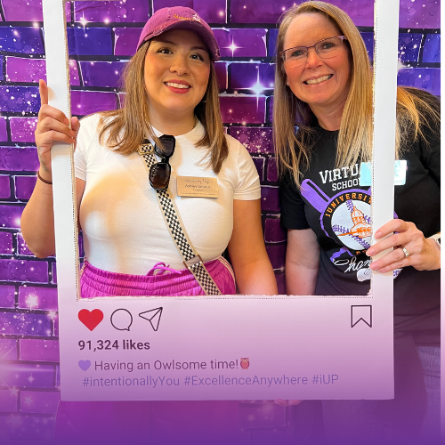 Two staff members smiling with a cardboard Instagram frame