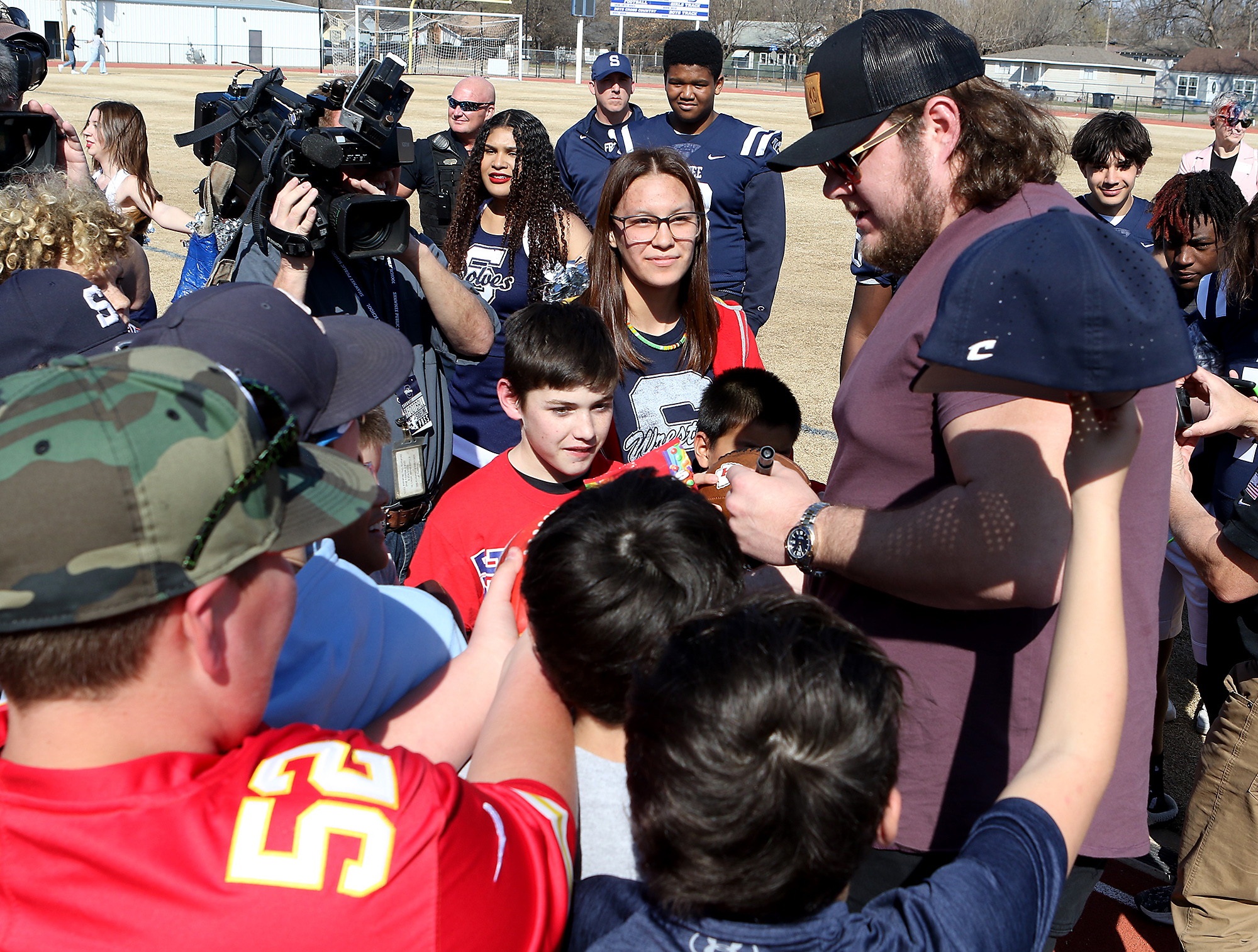 a man signs autographs for a group of children