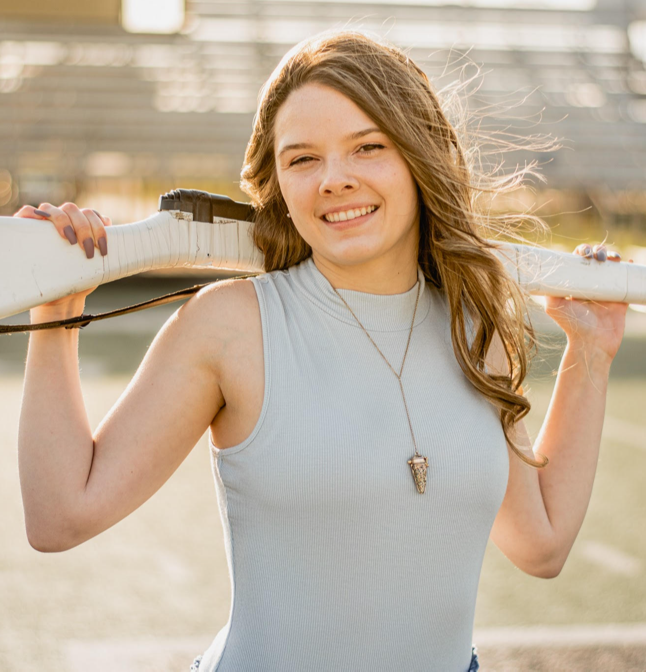 a woman holds a color guard rifle behind her shoulders