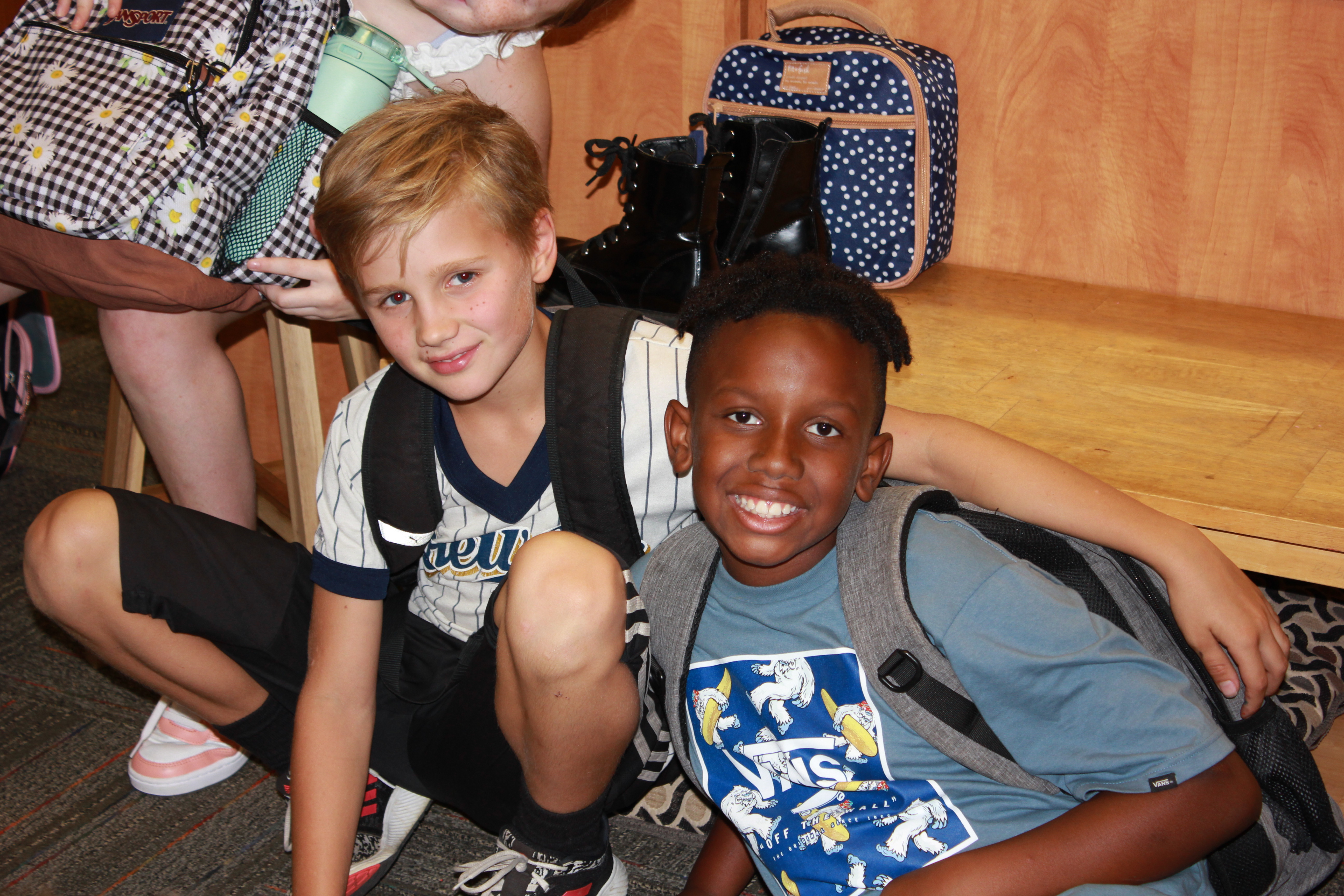 two middle school students with backpacks smiling at camera