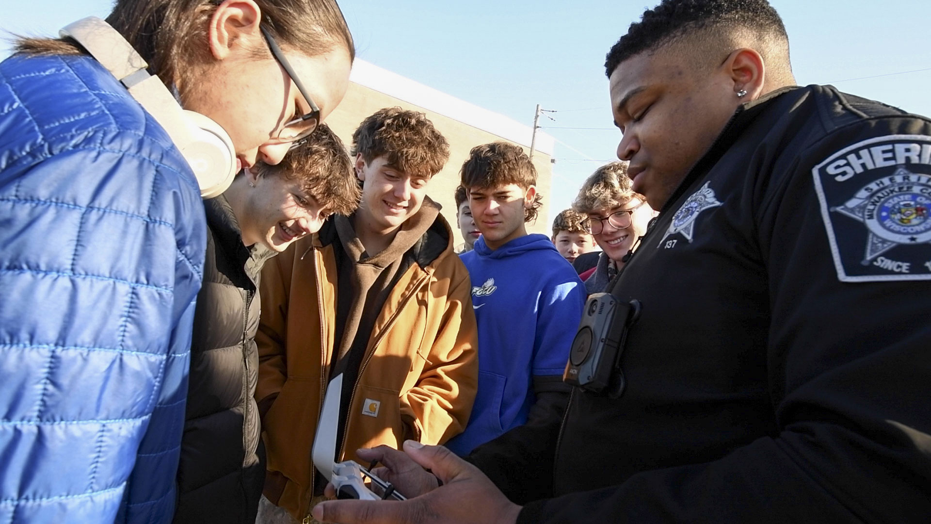 students looking at drone with deputy