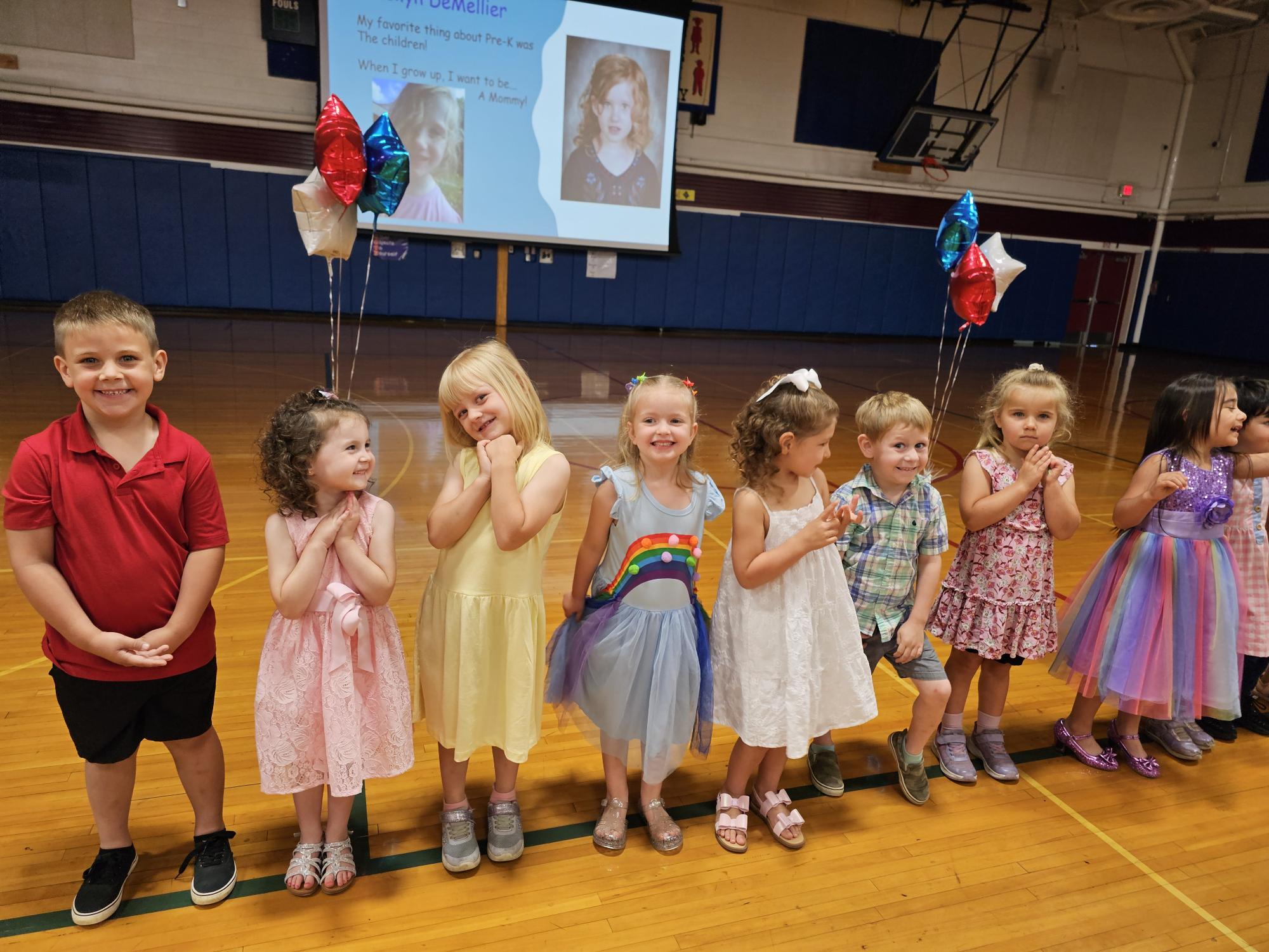 PreK Moving up picture, students posing standing in a line in the gym