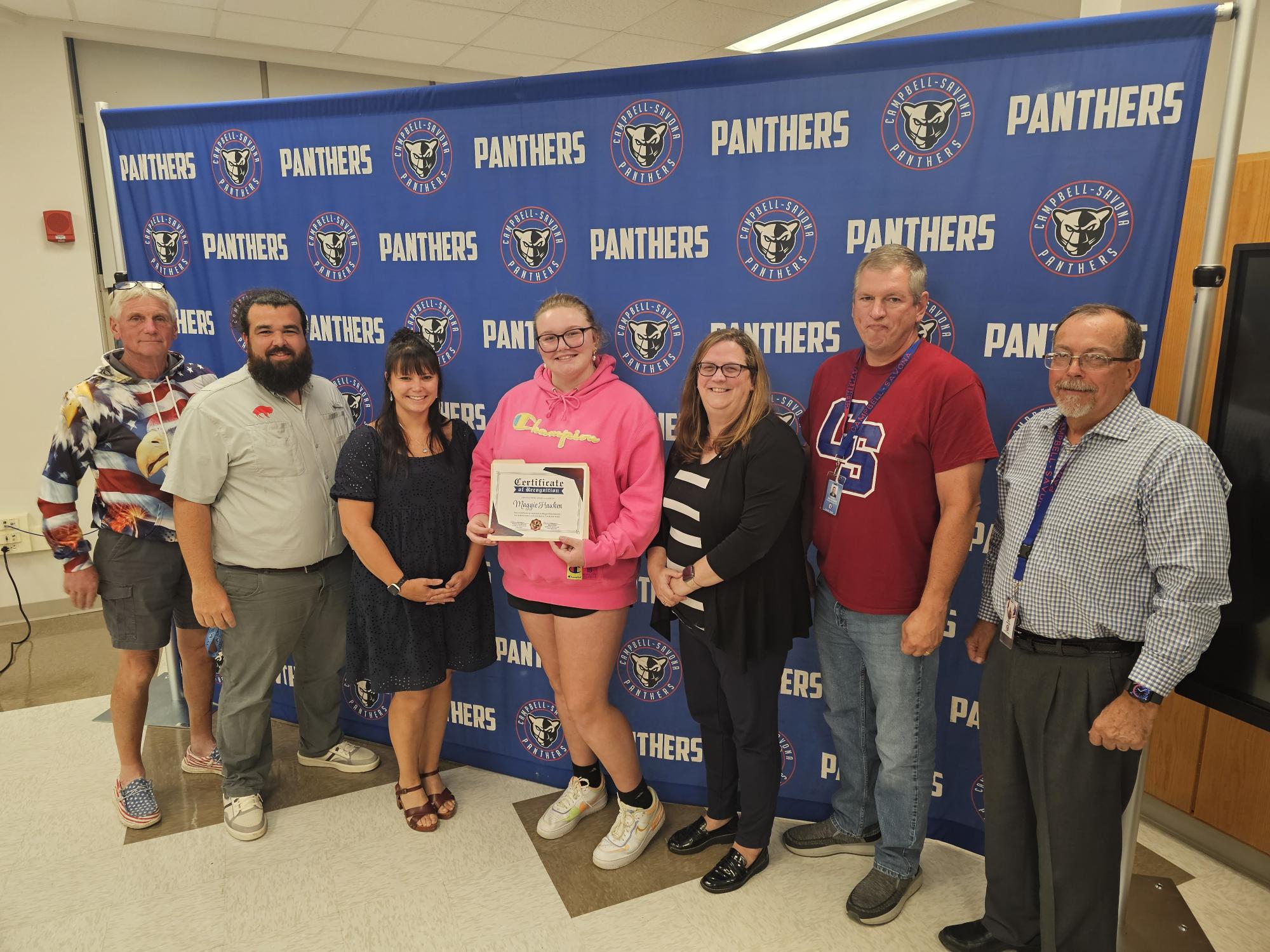 BOE posing with student in front of panther banner background