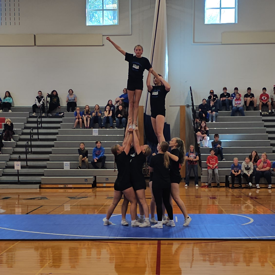 Cheerleaders holding studnet in the air dressed in black