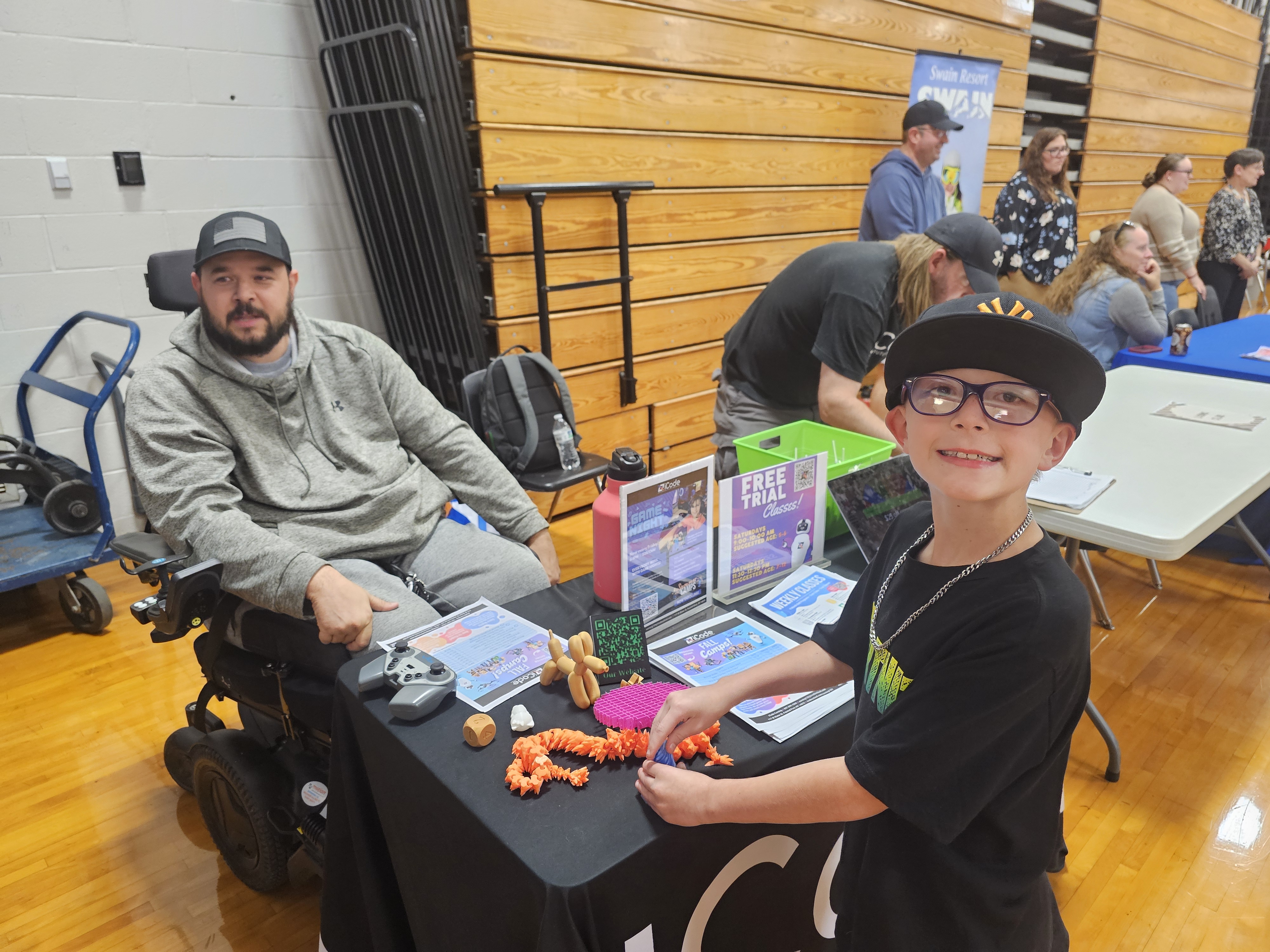 Student smiling at informational; table wearing a hat