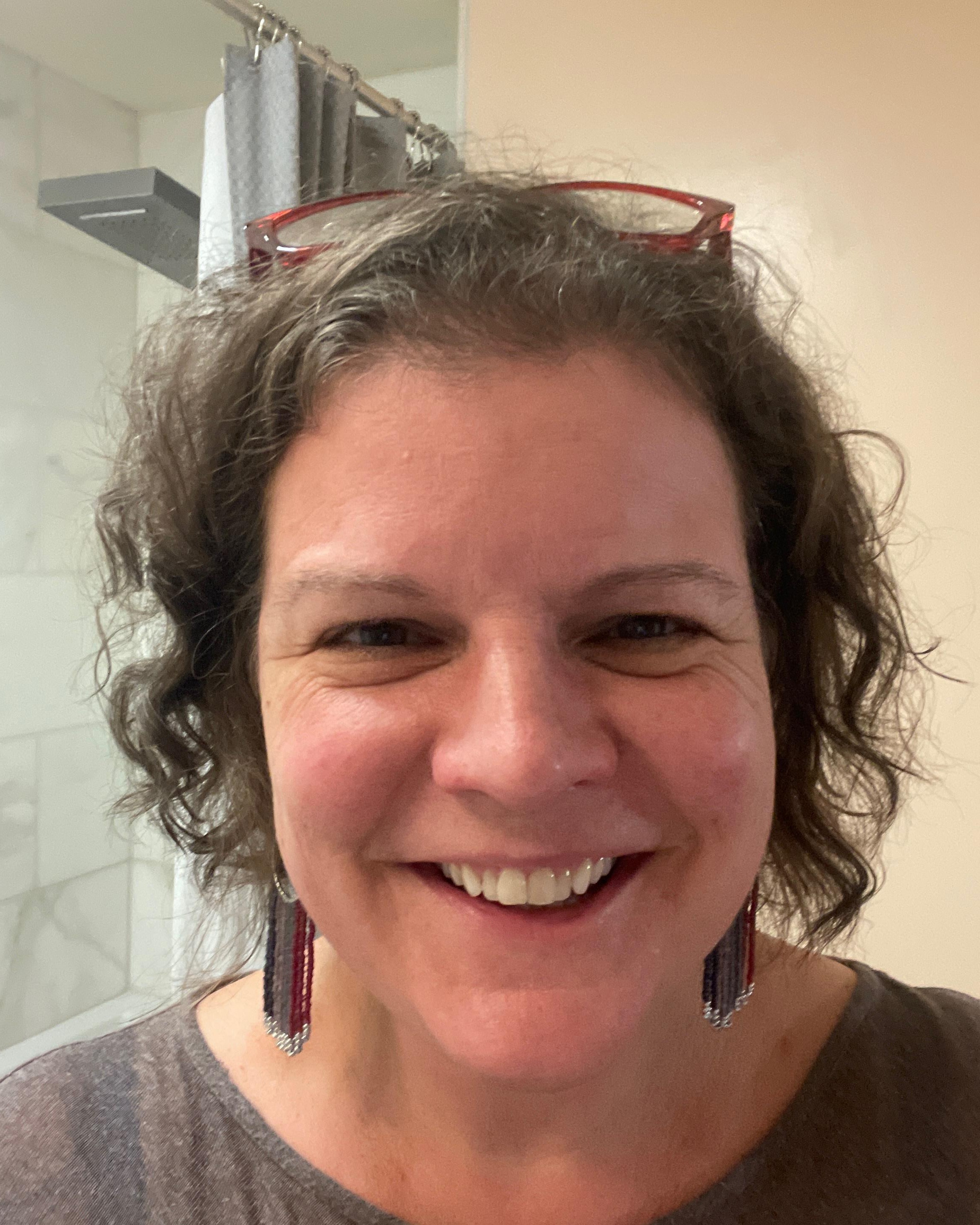portrait of women with smile brown hair and glasses up in her hair