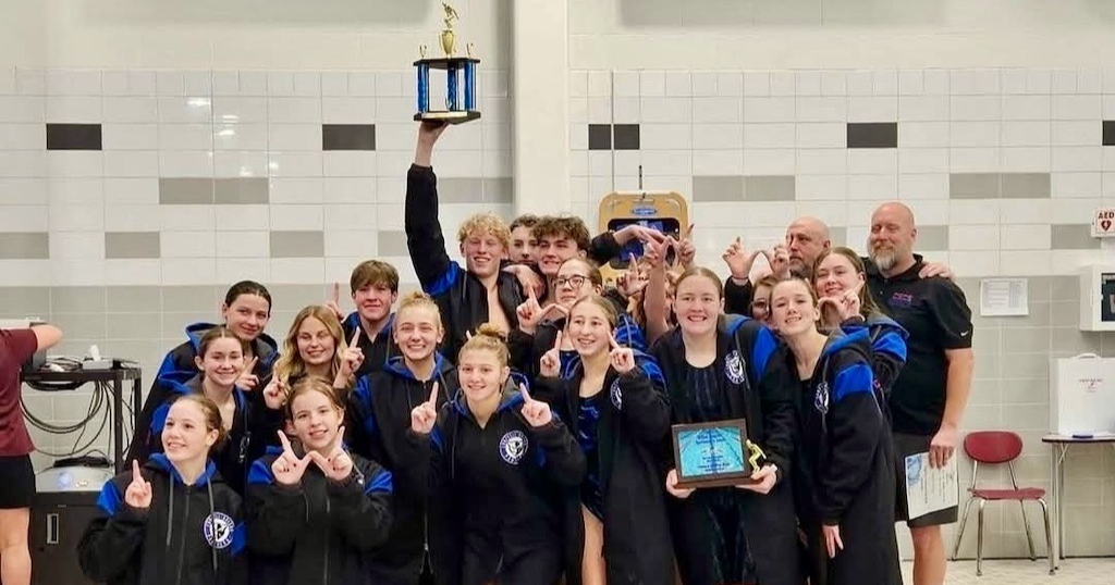 Swim team posing for picture with trophy