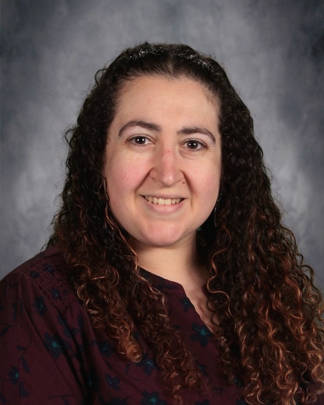 Headshot picture of teacher with long curly brown hair