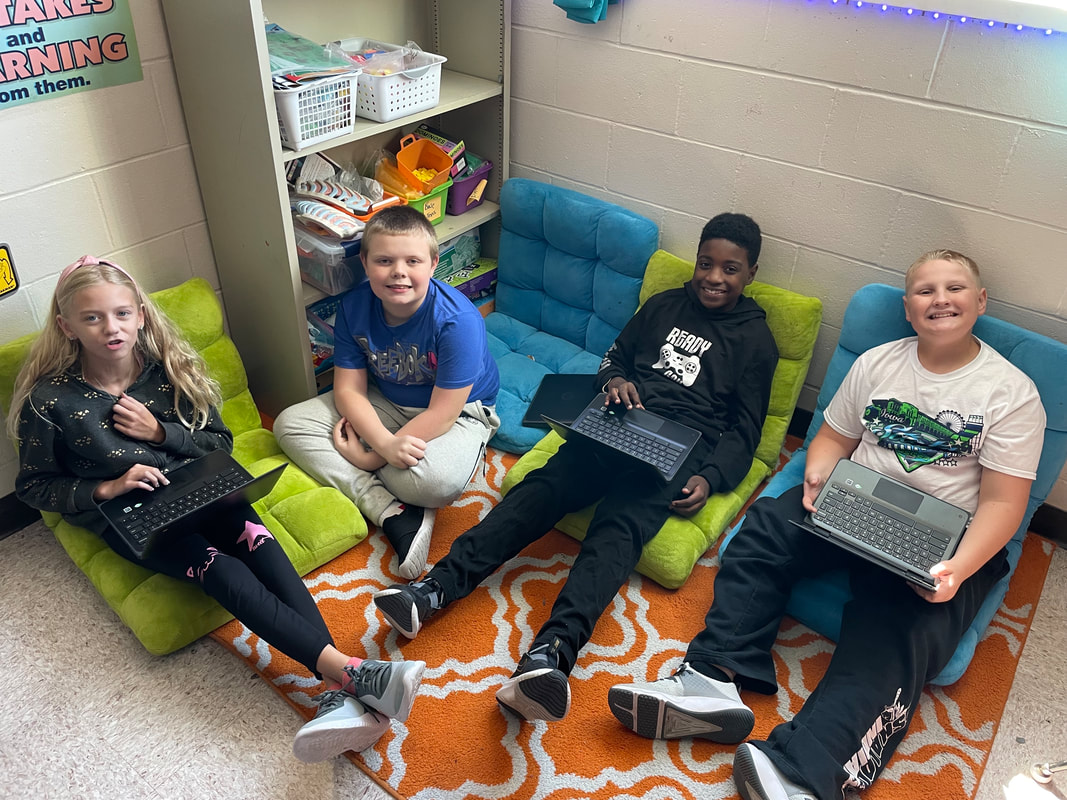 Kids sitting in a group on comfortable furniture with their chromebooks