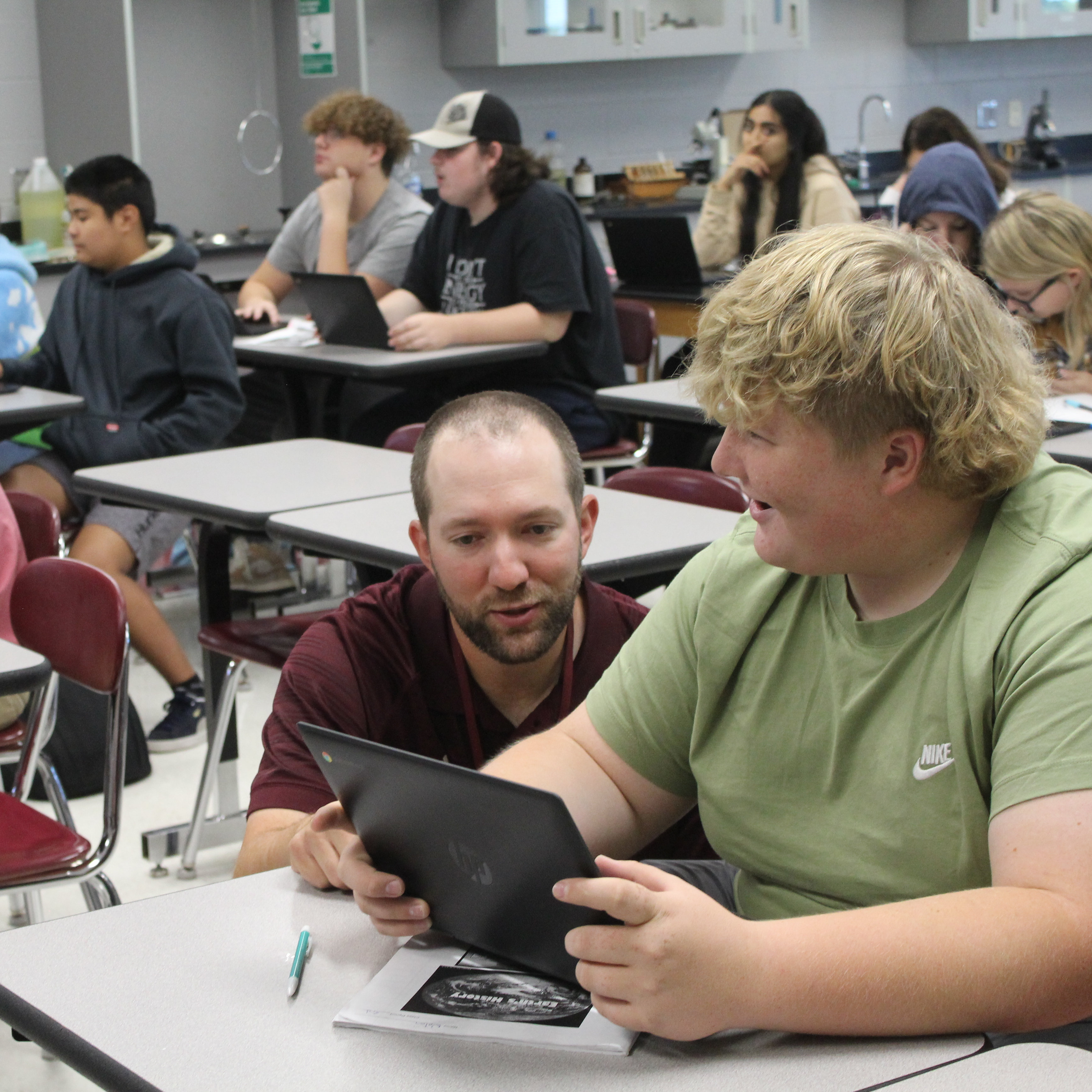 high school students sitting at desks in a classroom with teacher