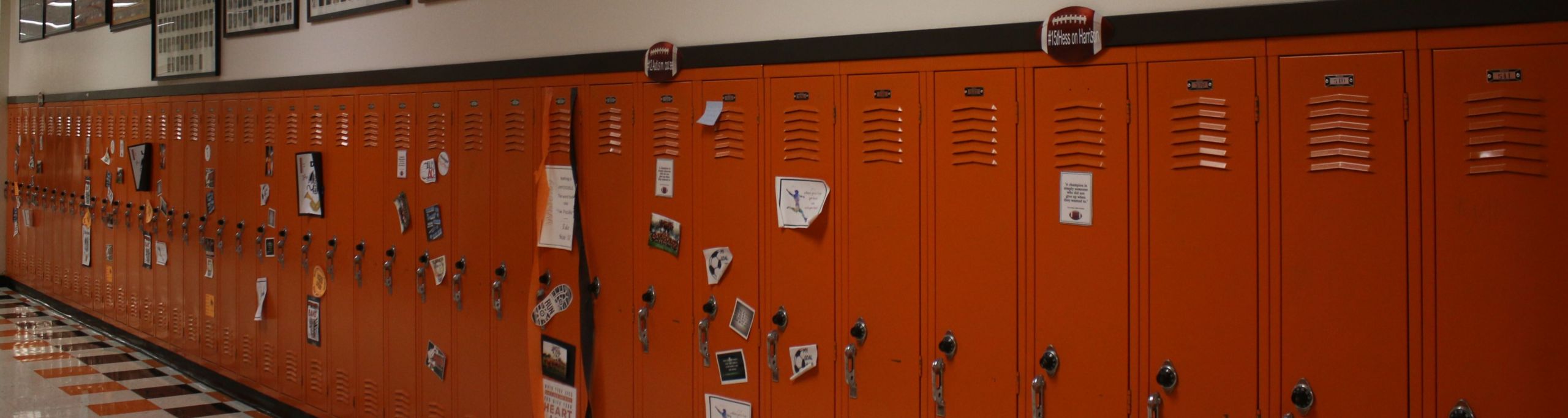 An image of a row of orange lockers with posters and flyers taped to them.
