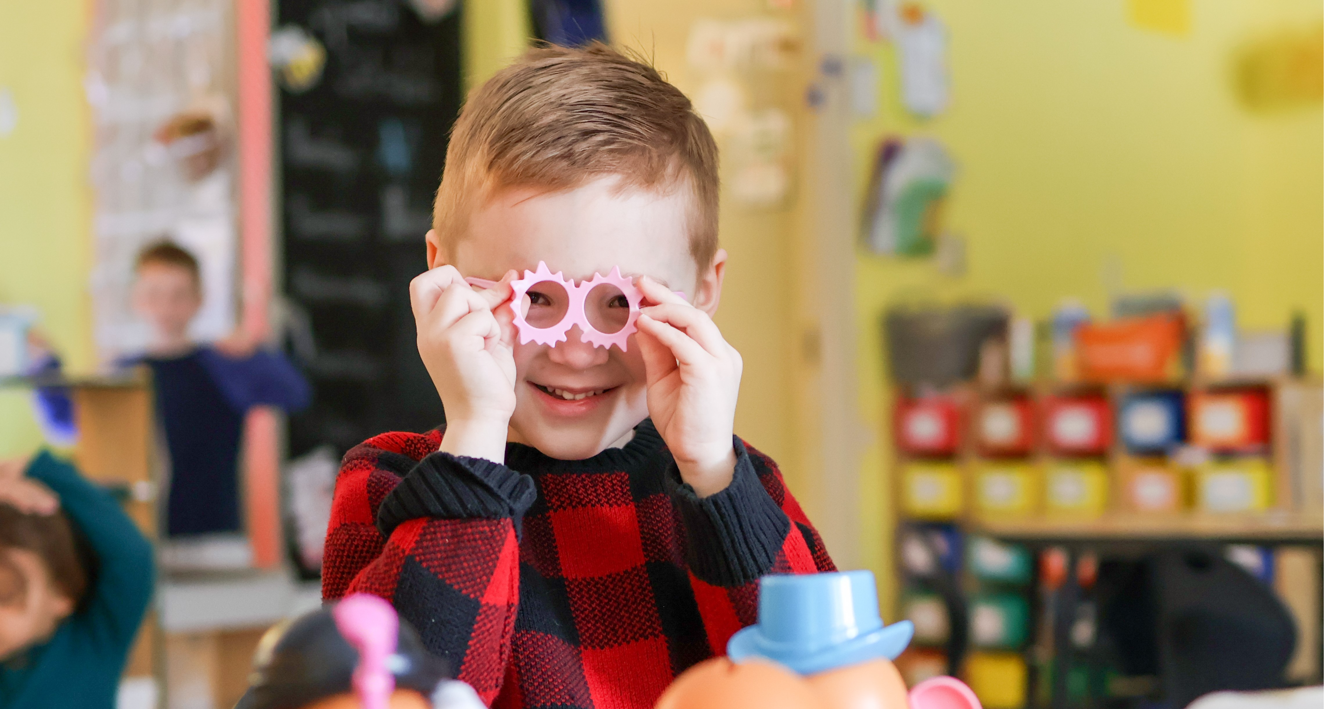 a boy smiles at the camera with silly glasses on