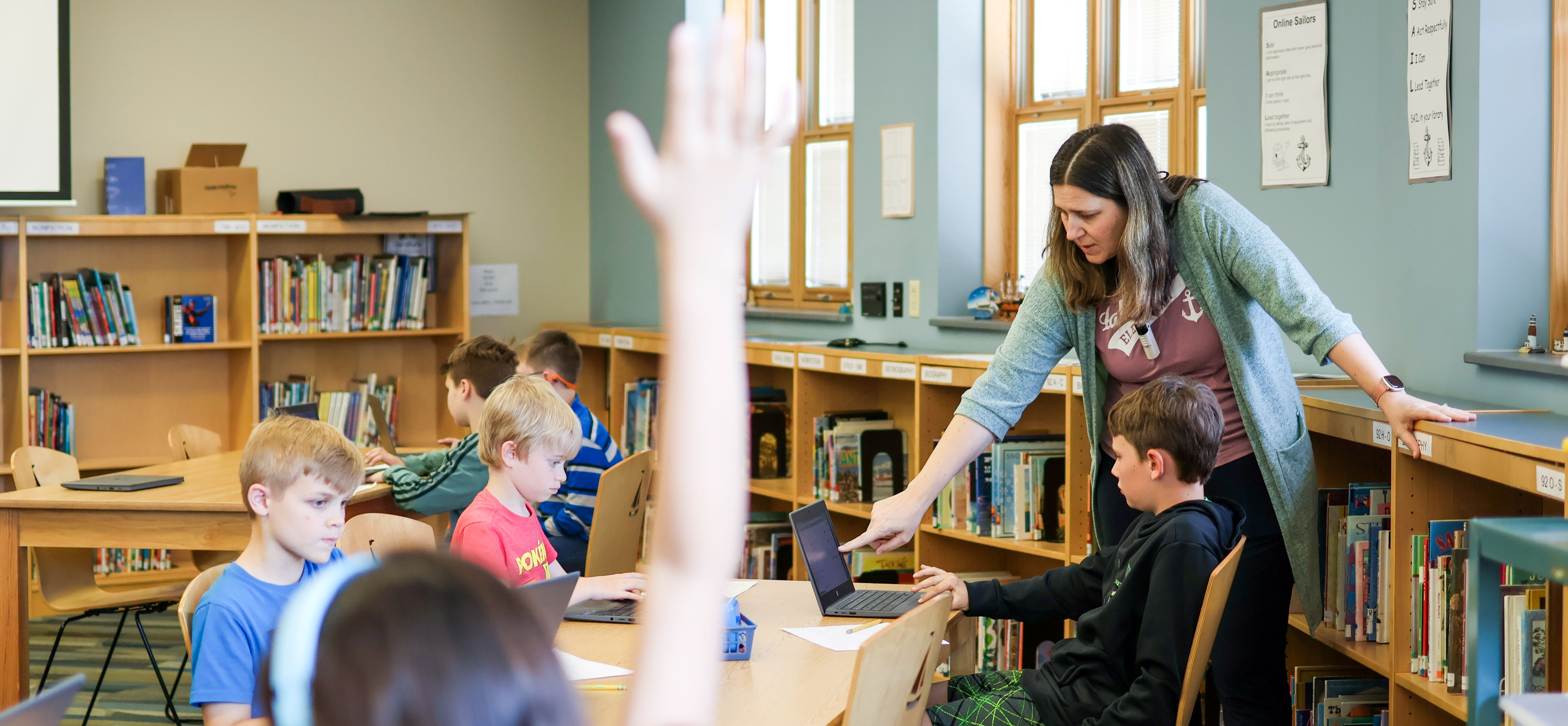 A teacher helps students work in the library